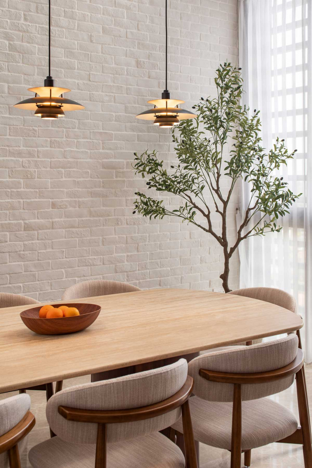 Louis Poulsen PH 5 Mini pendants cast a soothing glow over the lustrous travertine-topped table
