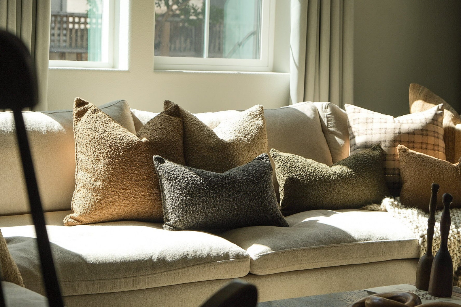 Twenty Third bouclé throw pillows arranged on a sofa, showing the textured surfaces in neutral tone