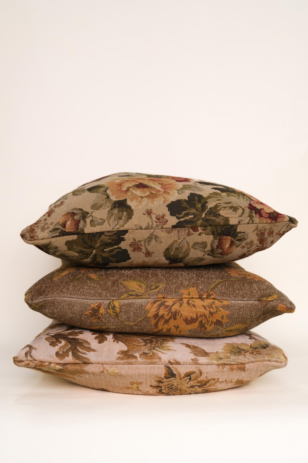 Three Twenty Third tapestry pillows stacked to show the floral patterns in earthy tones across different colourways