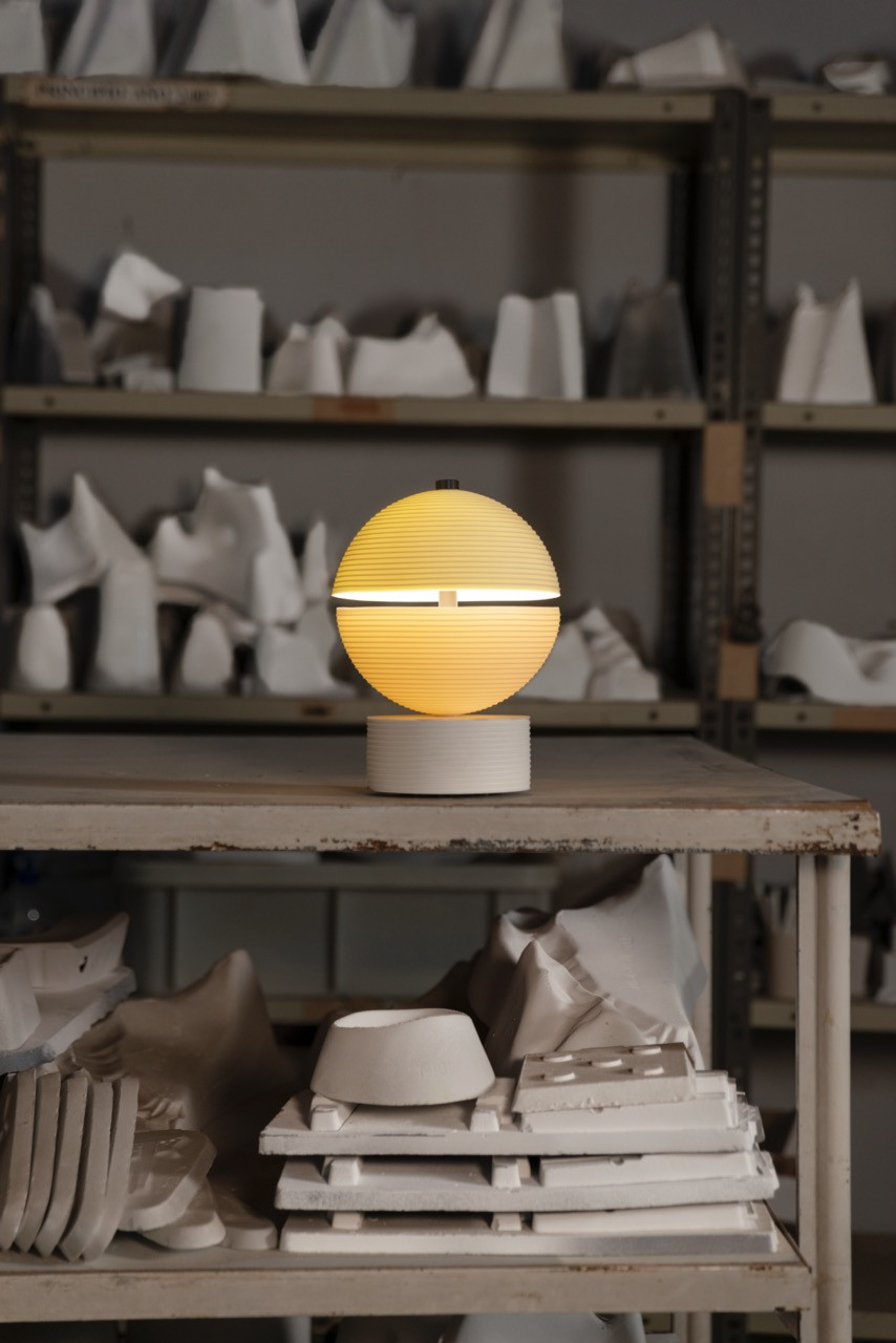 The Lee Broom Cascade Wireless Lamp for Lladró illuminated in the Spanish manufacturer's workshop, surrounded by porcelain production molds