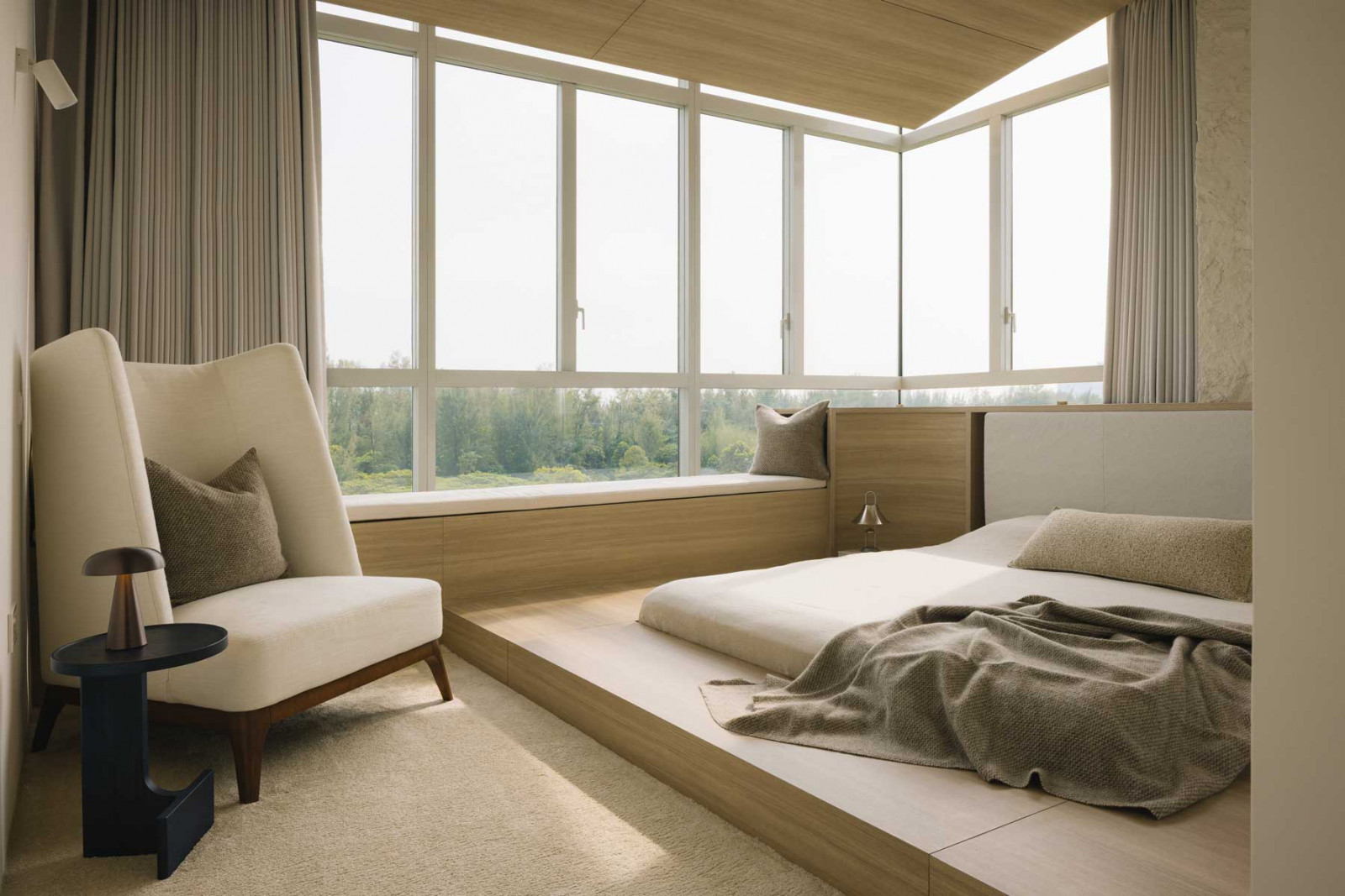 This bedroom offers an abundance of lounging options with its low-slung bed, armchair and bay window seat