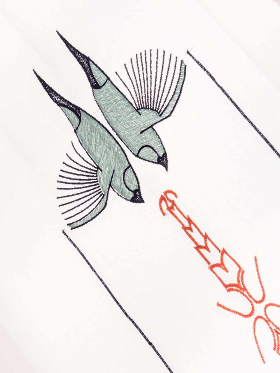 Close embroidery detail showing a kingfisher in teal and coral thread, one of the native bird species recorded on the textile panels