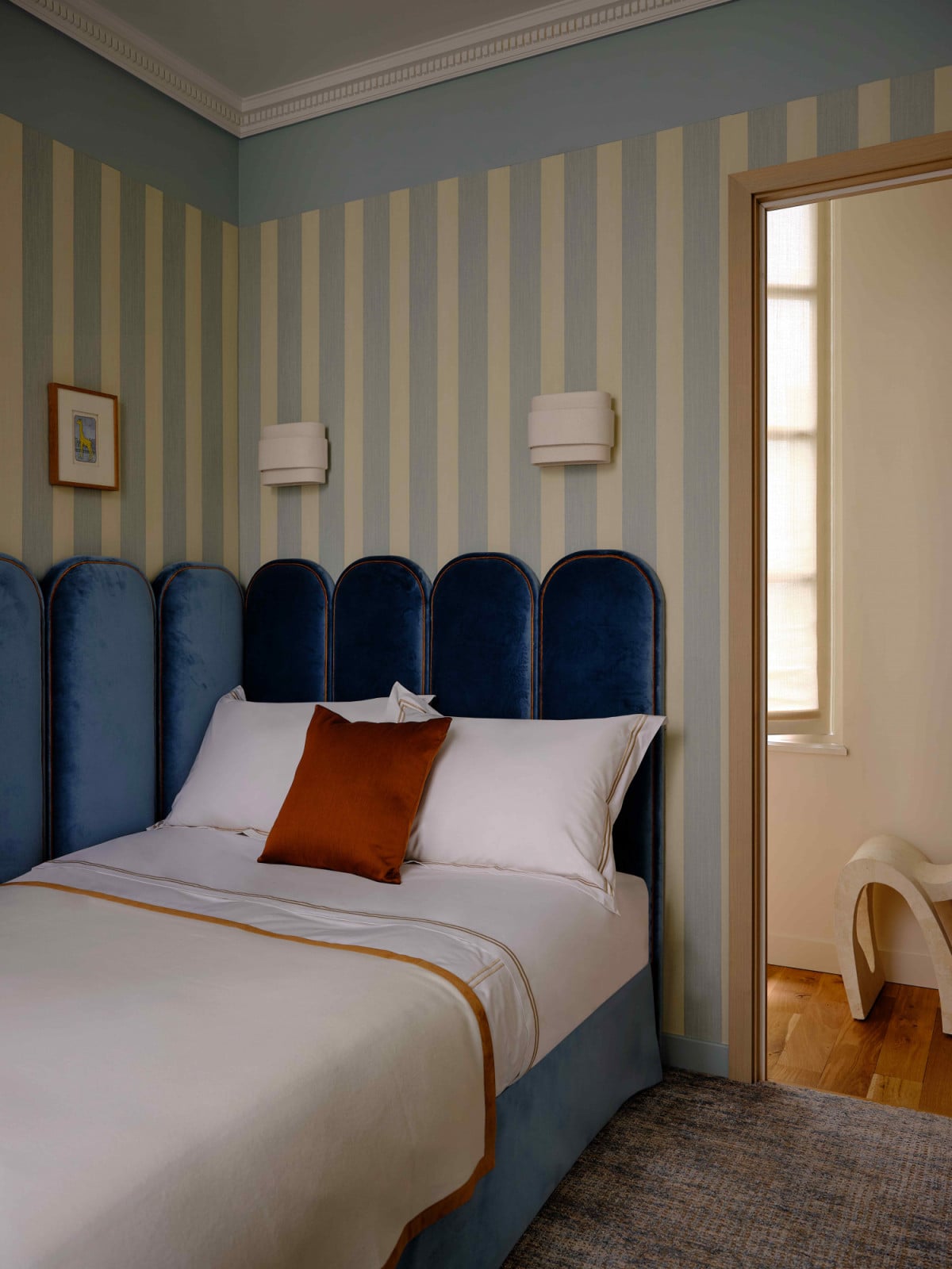 The velvet scalloped headboard in navy blue in the children’s bedroom