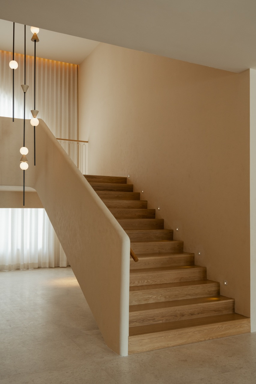 Stairwell with timber treads and integrated lighting, showing the warm material palette throughout the Mediterranean-inspired clubhouse