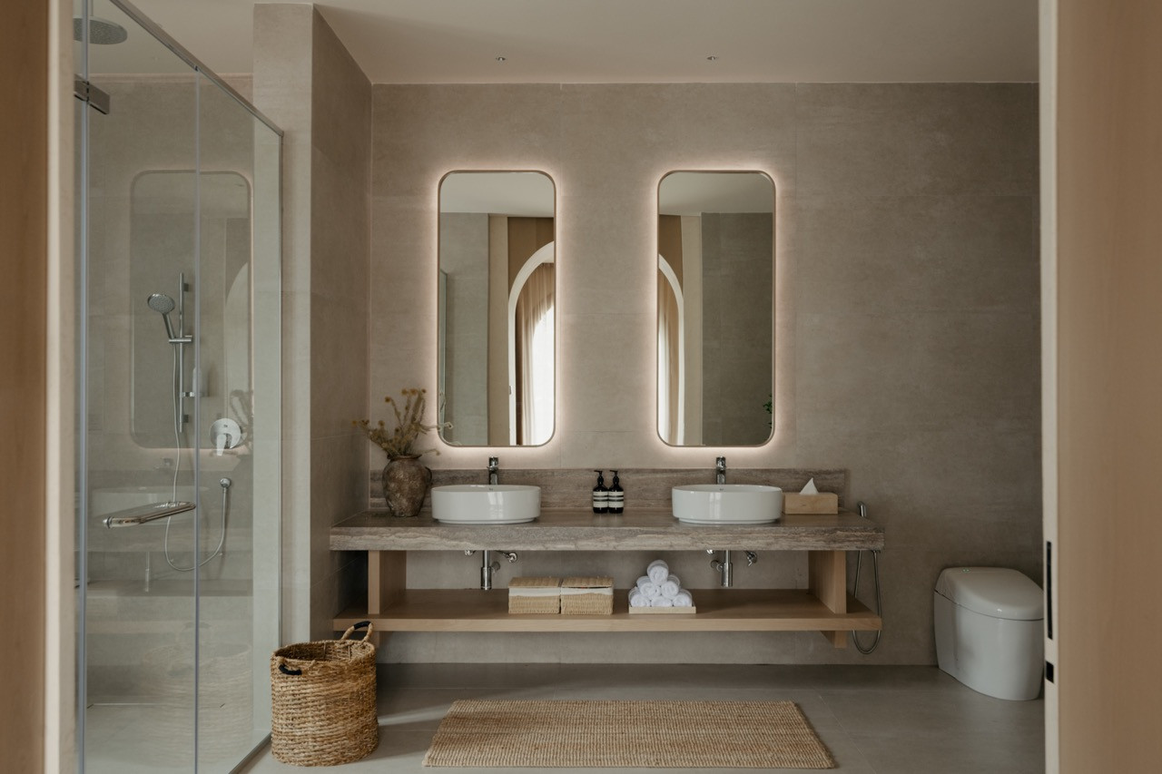 Guest bathroom with double vanity in light-toned stone, part of the Mediterranean-inspired material palette