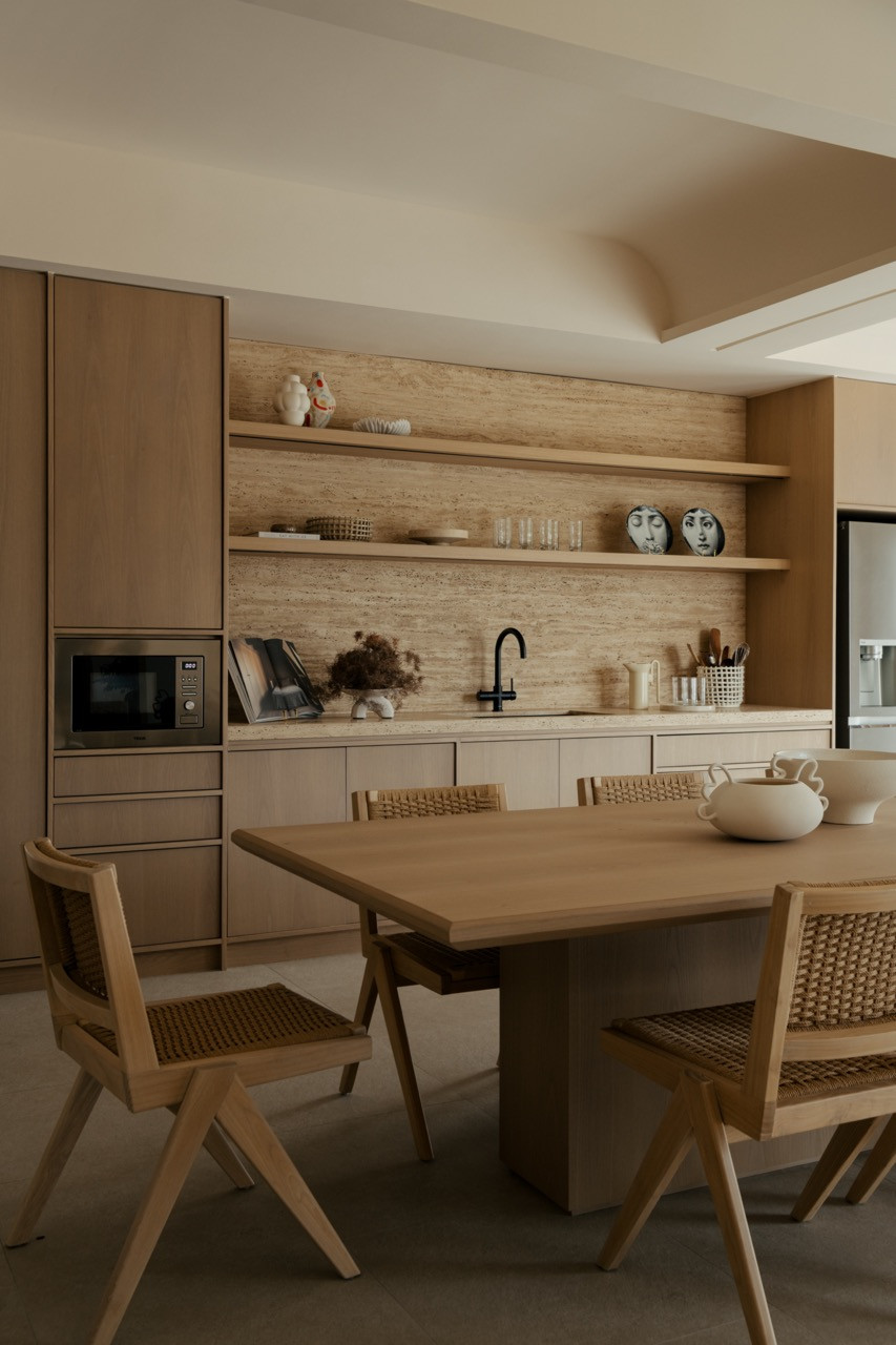 The kitchen area, with Jessica Hans vase from HAY and Fornasetti face-print plates on timber shelving, alongside Joot dining chairs