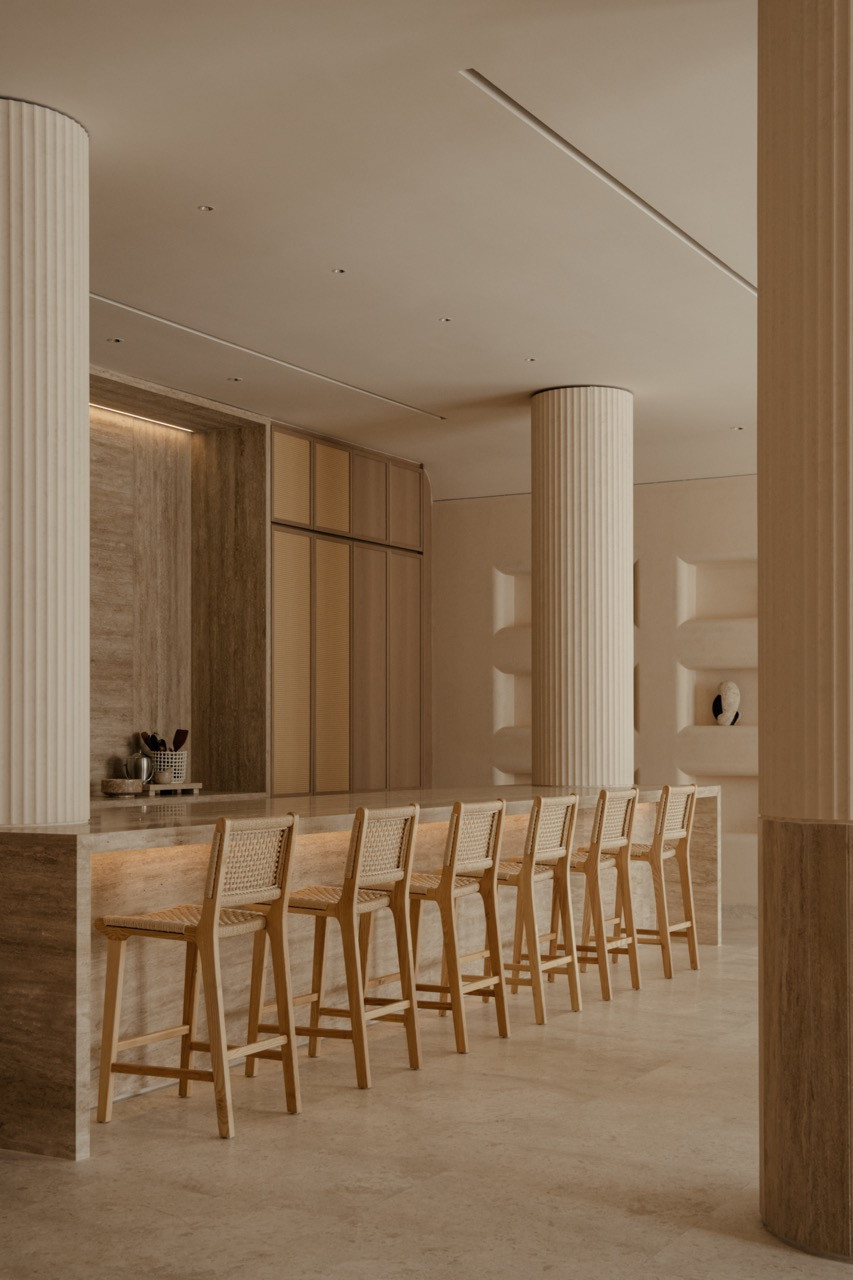 The omakase bar with caned bar stools lined along the stone counter, flanked by fluted columns
