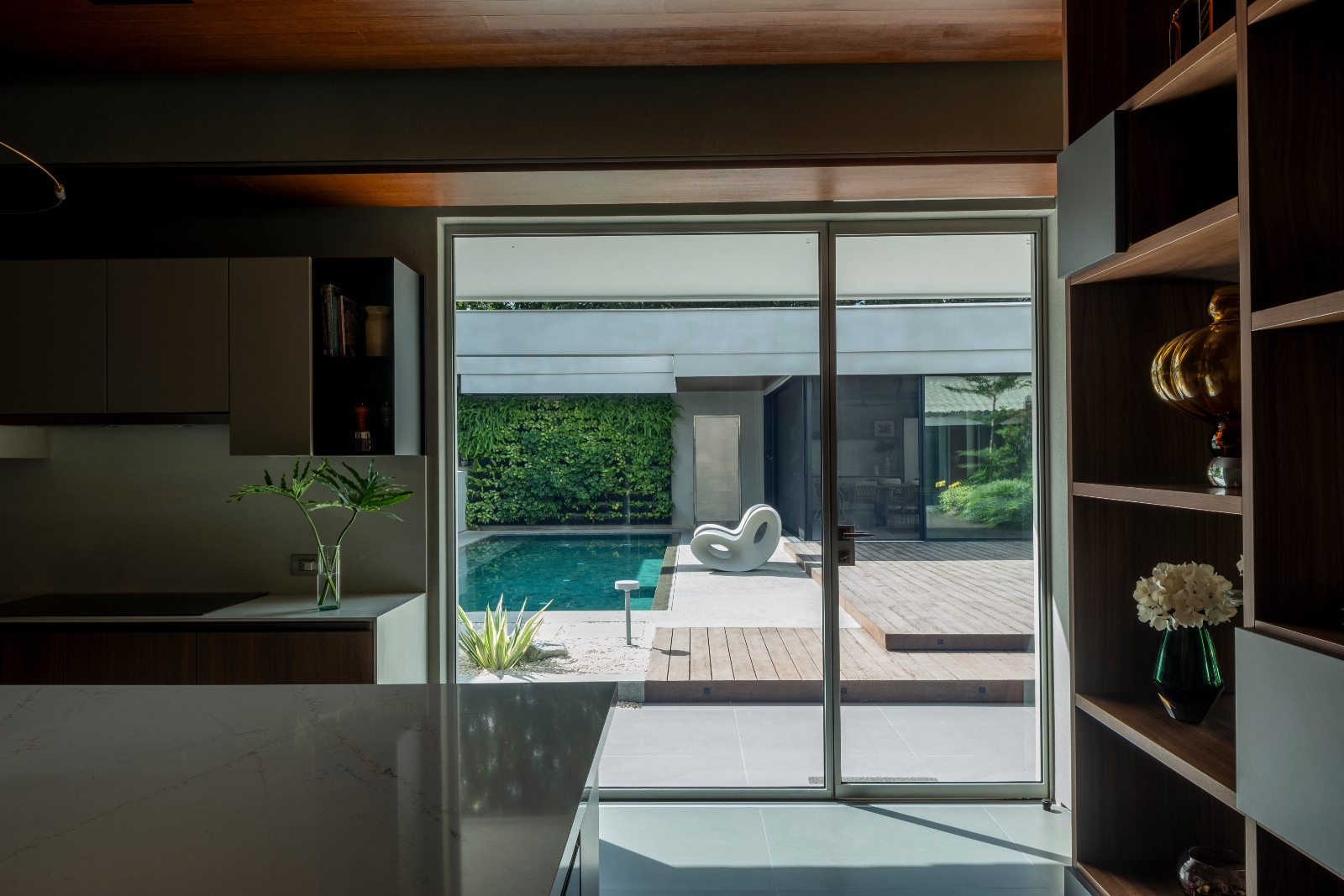 The kitchen leading to the outdoor pool area of a Manila, Philippines home designed by Lino Architecture