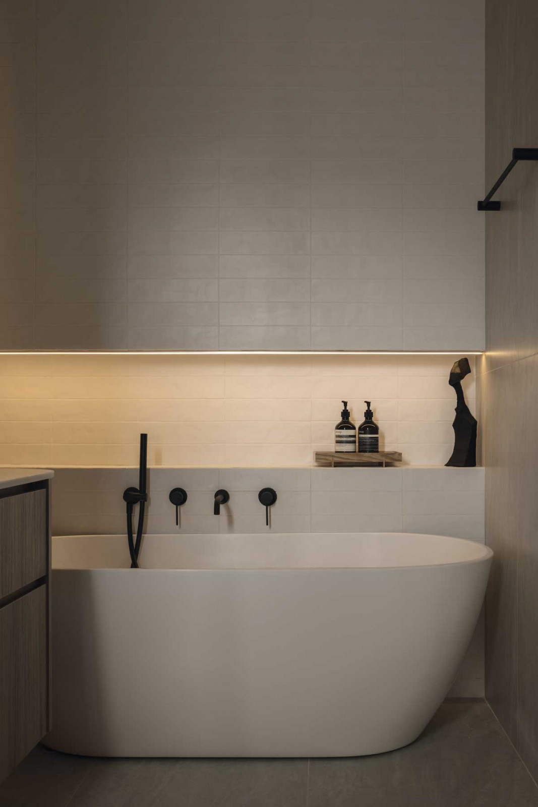 Dark accents and ambient lighting imbue this bathroom with an atmospheric air