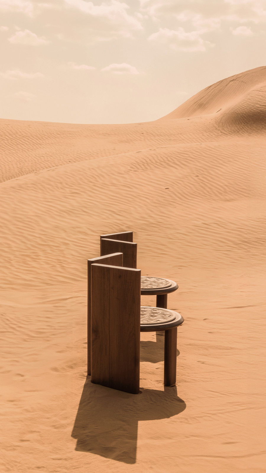 Jagdish Sutar’s stool from the Objects of Legacy collection, photographed in Rajasthani desert sand, featuring carved geometric woven seats on teak frames with stepped vertical supports