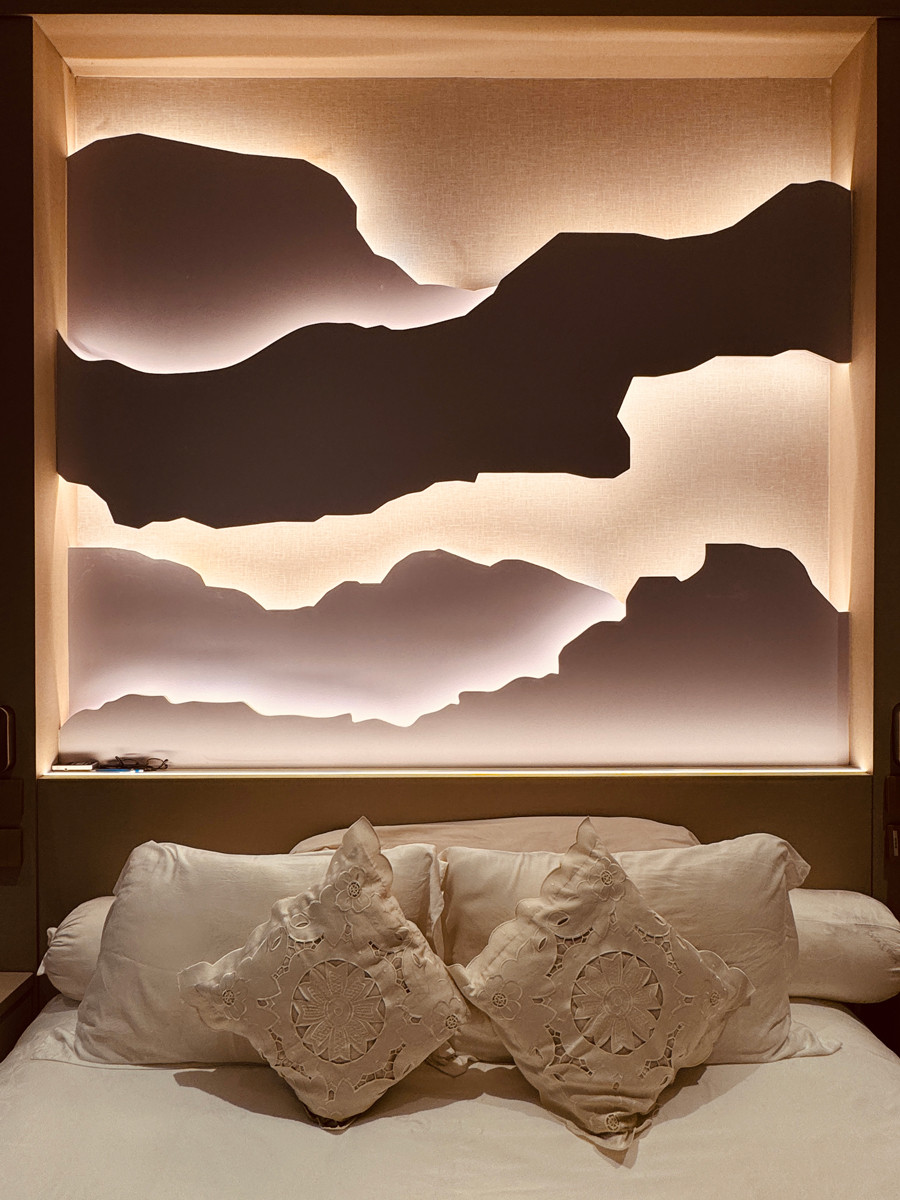A softly illuminated art box above the bed introduces a shadow-box effect, lending the space a sense of depth