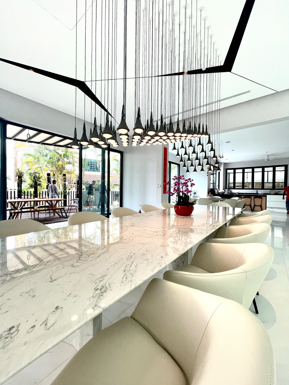 The dining room ceiling is articulated with geometric forms that echo the lighting installation in the adjoining living area