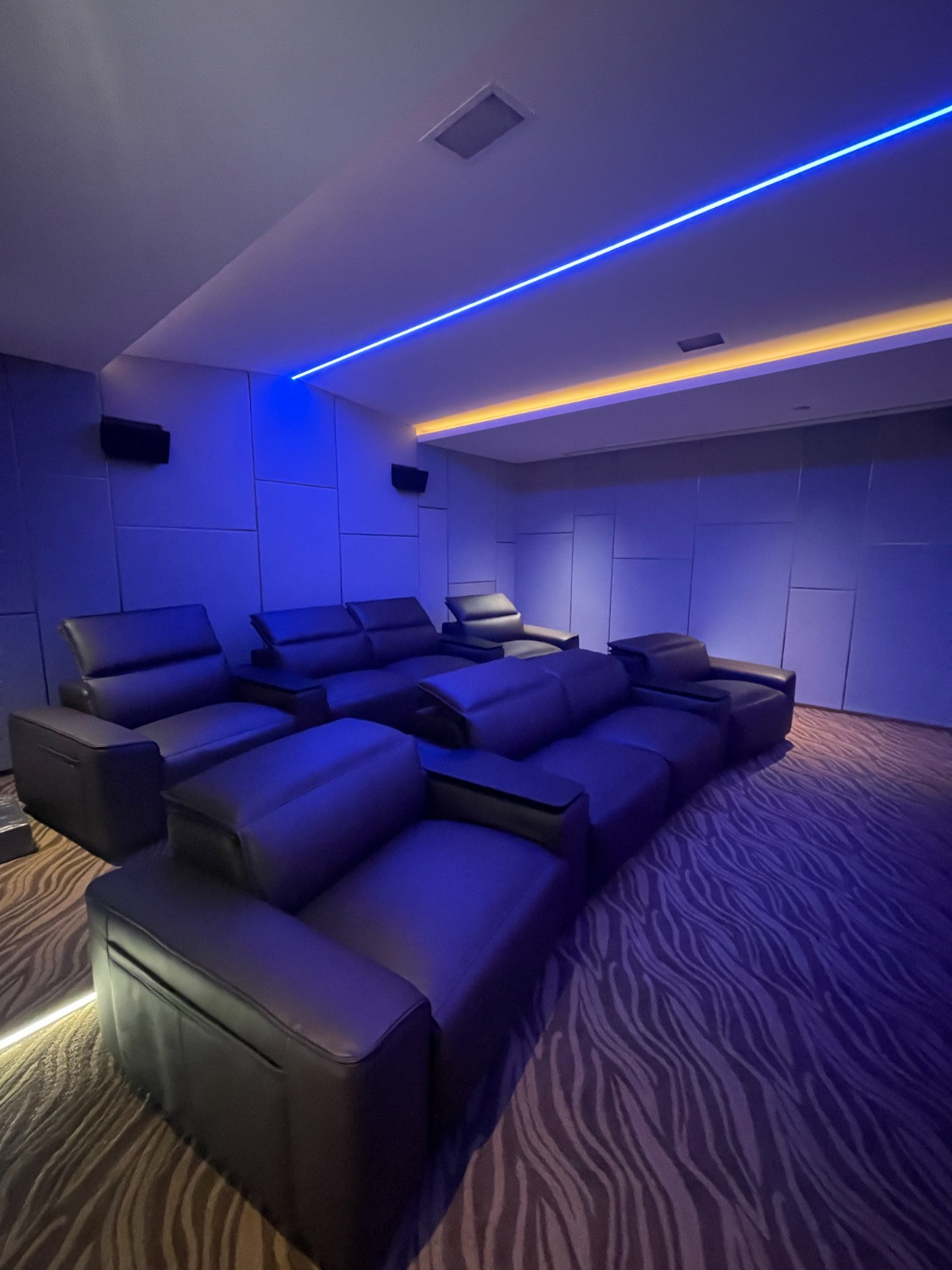 Subdued lighting in blue hues lends the multigenerational home theatre a cinematic, immersive quality