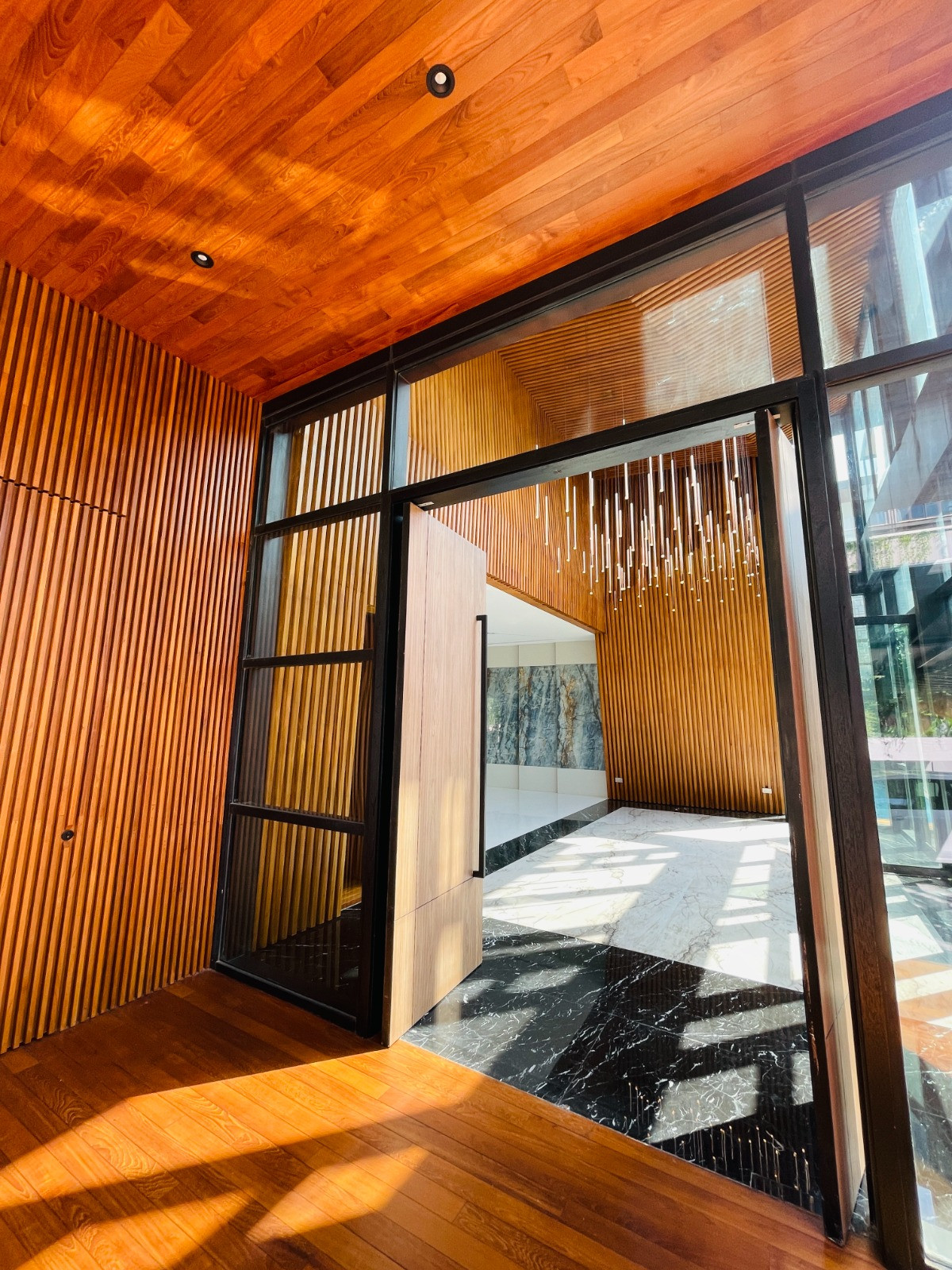 Timber finishes in rich tones line the entrance procession, lending the arrival sequence a sense of continuity and tactility
