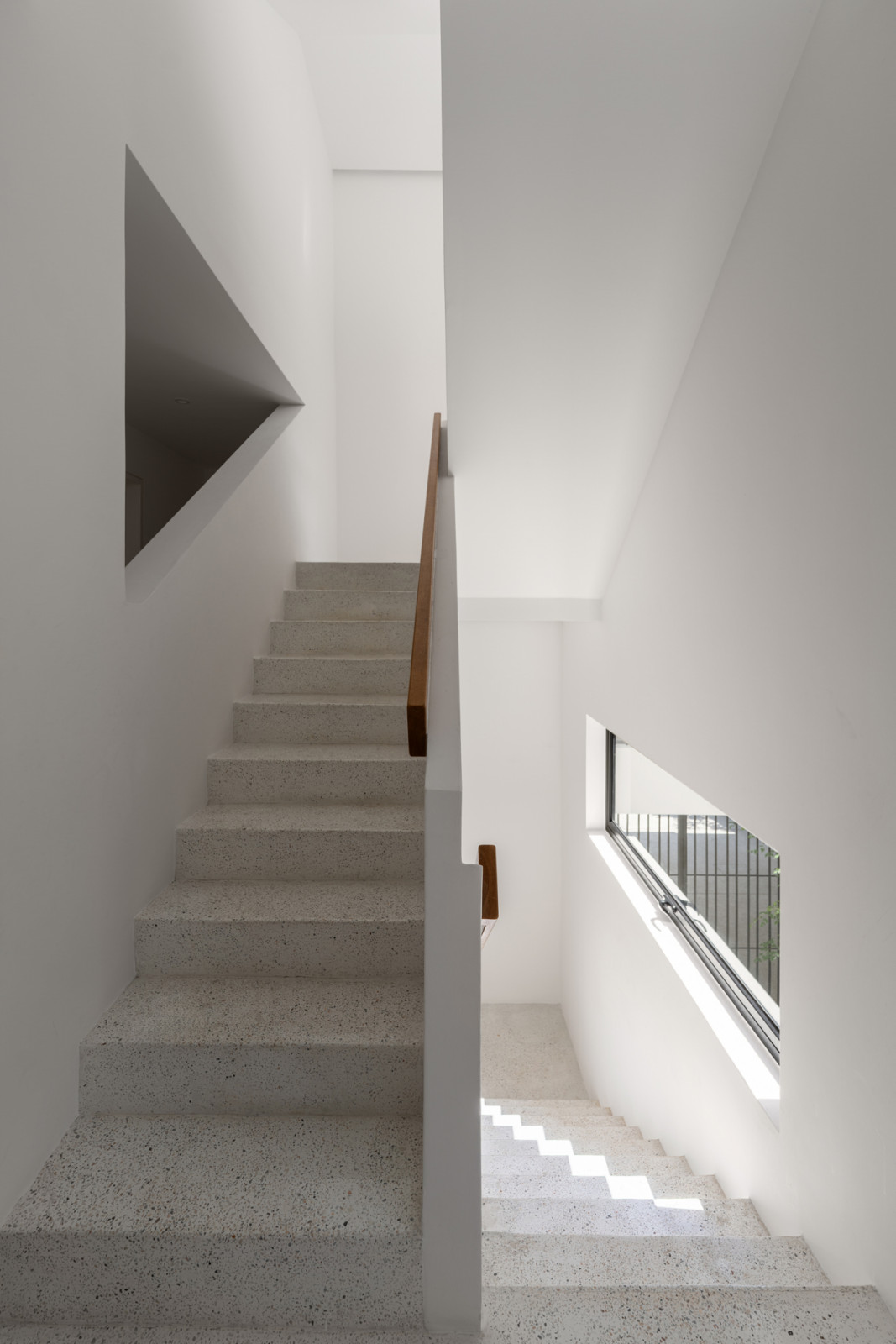 The stairwell connects the three floors with terrazzo steps and white-rendered walls