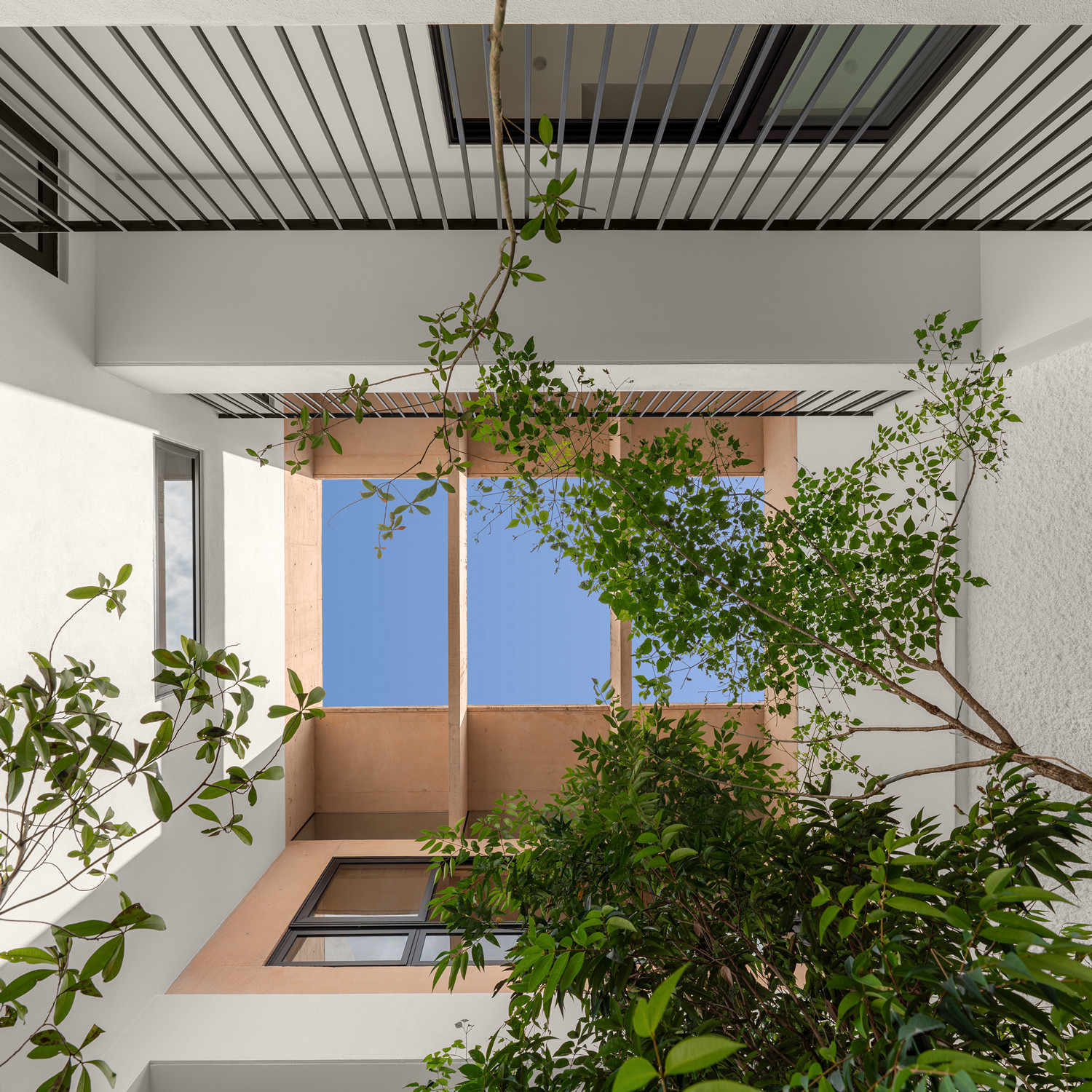 Looking up through the central courtyard, the pink concrete structure frames views of the sky
