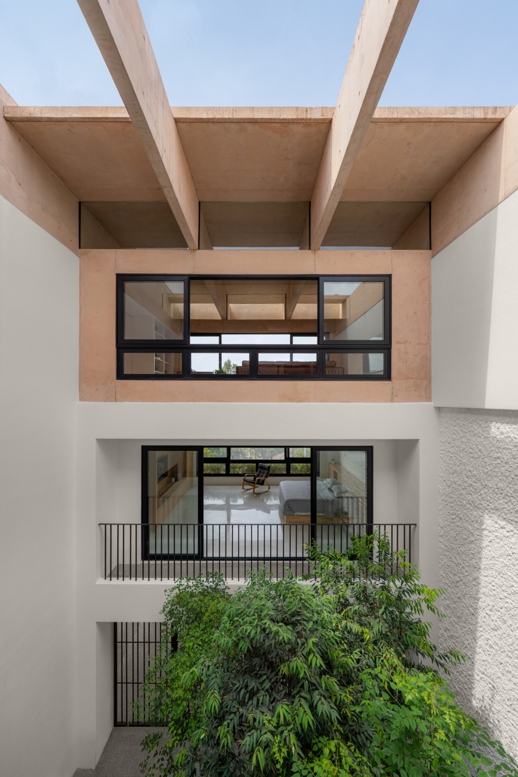 The central courtyard viewed from below shows how the beams in the extended unit pierce lengthwise through the space, creating a visual dialogue with the perpendicular beams in the original unit