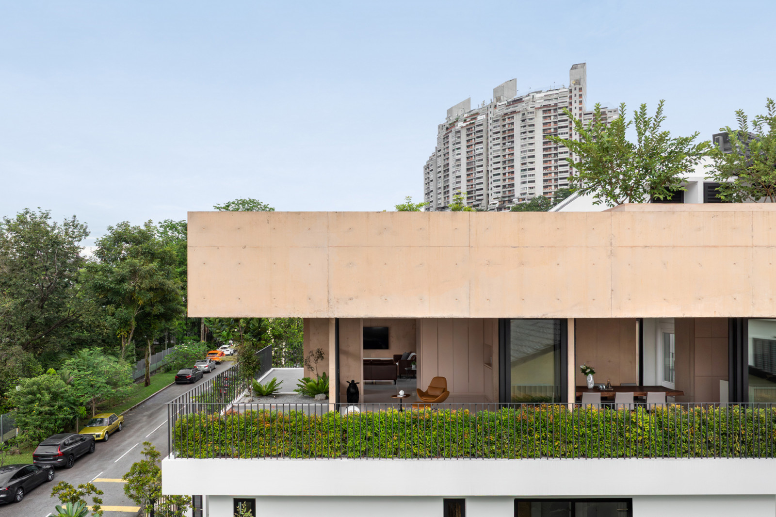 The pink concrete third floor sits above two white-rendered lower levels