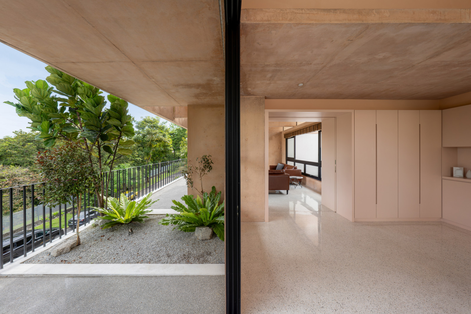 The third-floor living area opens fully to the planted balcony through sliding glass doors