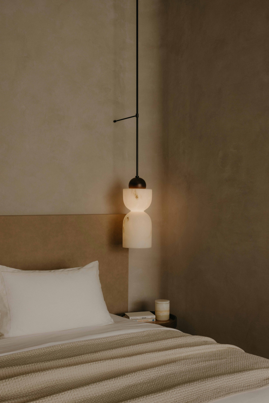 A sculptural marble pendant light replaces a conventional bedside lamp
