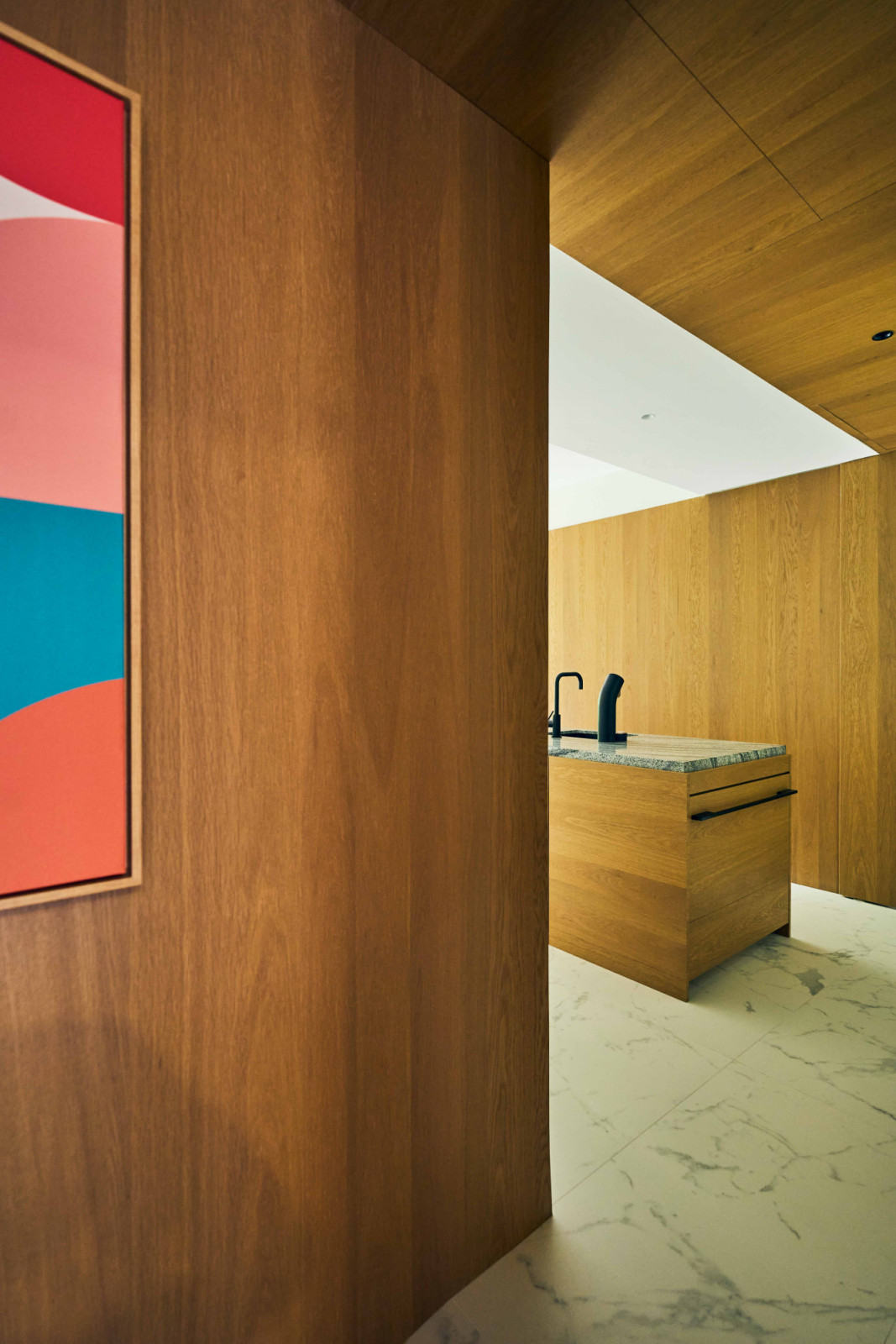 A corridor view towards the kitchen with Bauhaus-inspired artworks and mid-century modern accents
