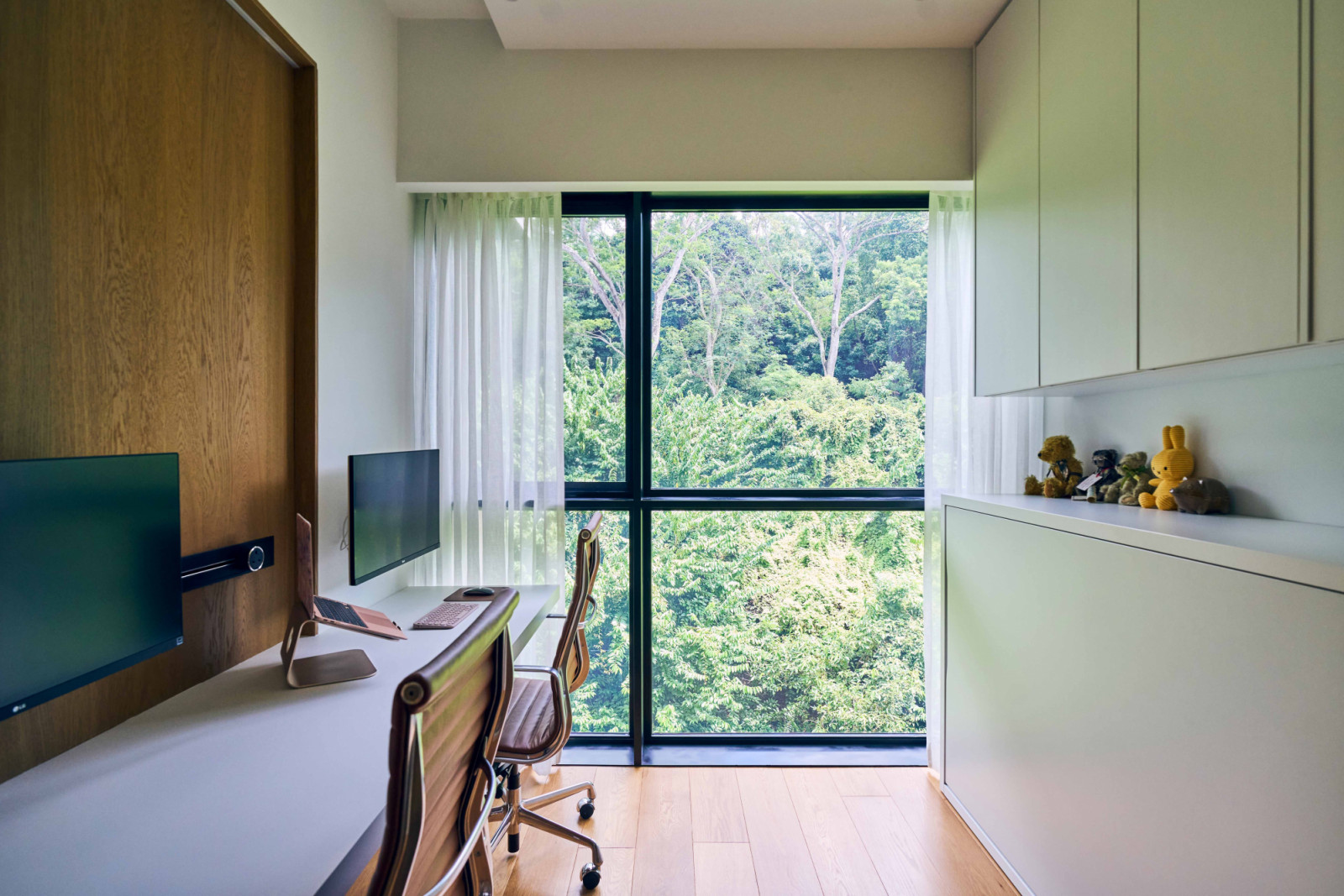 The mid-century modern-inspired apartment’s shared home office looks out towards the surrounding greenery.