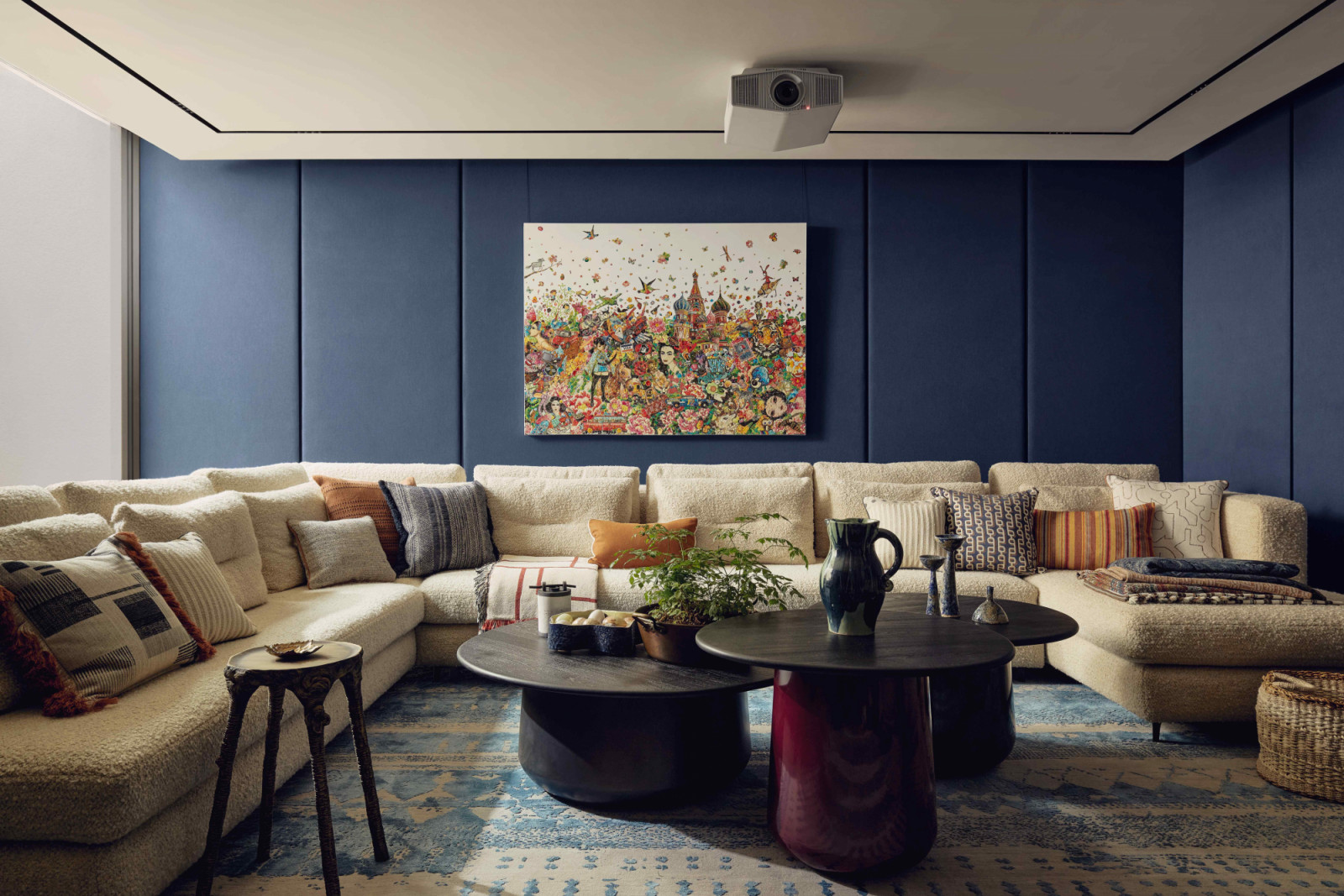 The cinema room in the basement with padded fabric wrapped panels in Villa Nova, Torrin, anchored by a vibrant artwork by Ye Hongxing