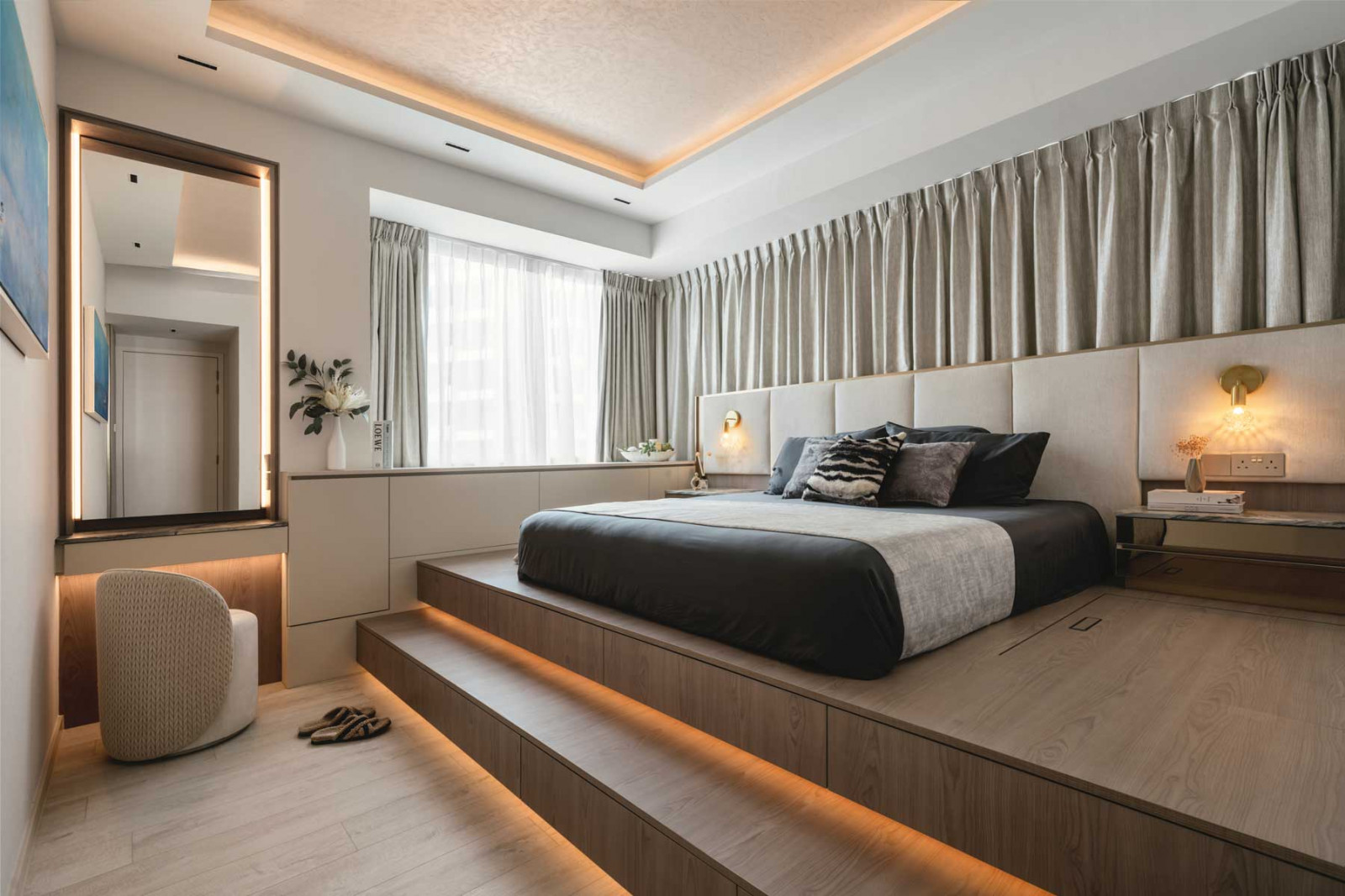 An elongated bay window in the master suite was augmented by the addition of custom cabinetry and cocooning curtains, forming a cosy nook in the room