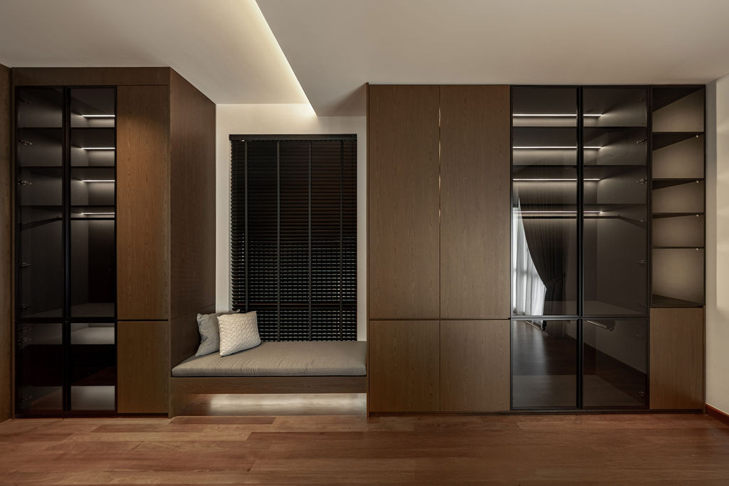 A bedroom features glass-fronted wardrobes with integrated lighting and a built-in window seat beneath concealed ceiling fixtures