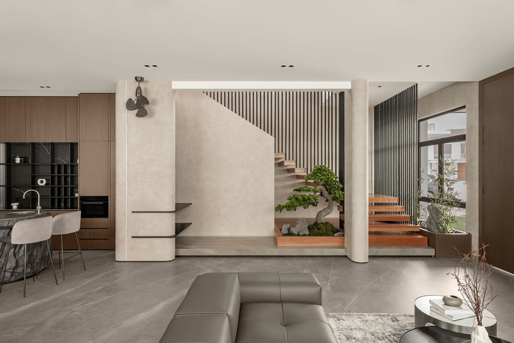 A bonsai installation sits at the base of the staircase, framed by vertical steel slats and micro-cement columns