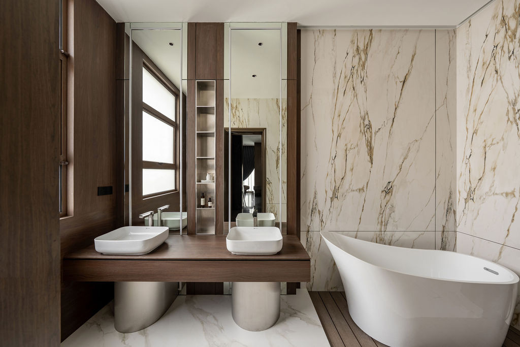 The bathroom pairs veined marble walls with a timber floating vanity and freestanding tub