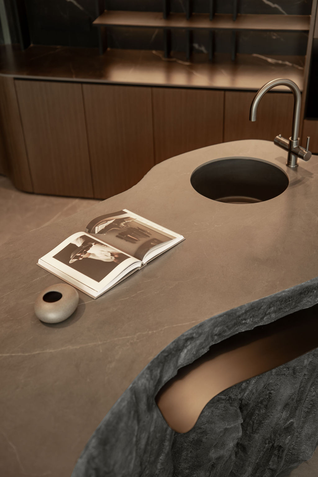 The stone island’s smooth top surface contrasts with its textured, hand-worked base