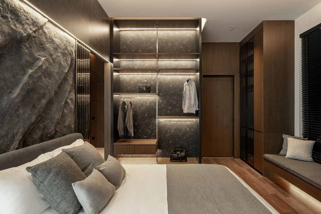 The bedroom's textured stone feature wall is backlit to create gradient lighting, while an integrated wardrobe features concealed illumination