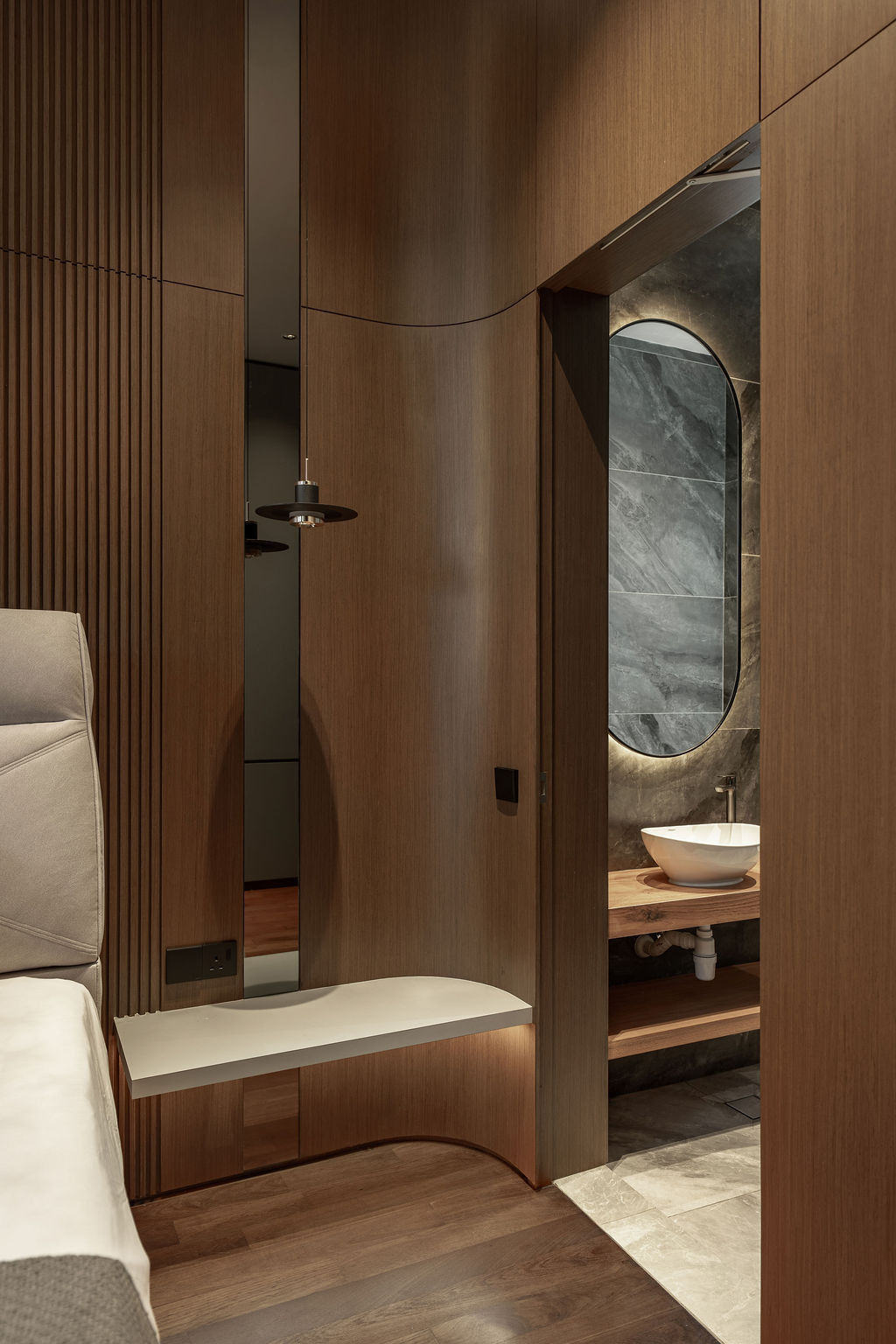 Curved timber cabinetry leads to an ensuite bathroom where stone walls are visible through the arched doorway