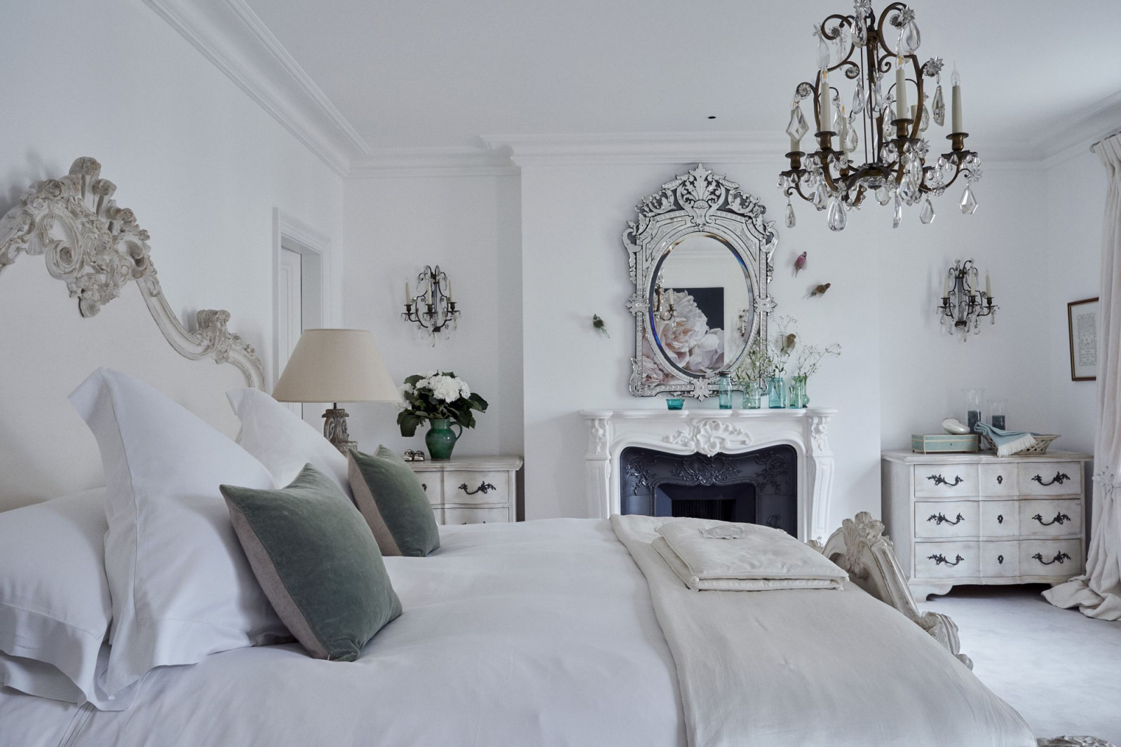 The timeless elegance master bedroom with an intricately carved timber bedhead and an antique Venetian mirror above the carved marble fireplace (Photo: Moreno Masey)