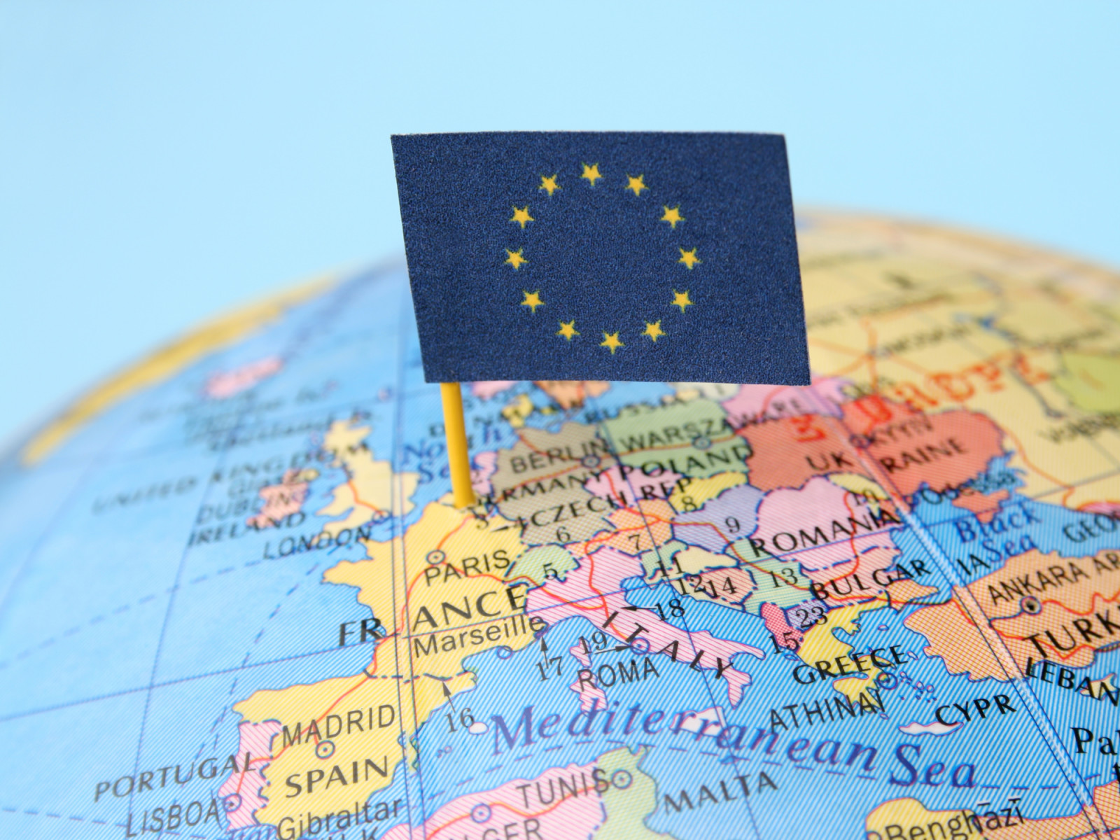 European Community flag over cheap plastic map pointing Brussels city, where its headquarters are found. Shallow depth of field (ภาพ: FotografiaBasica / Getty Images)