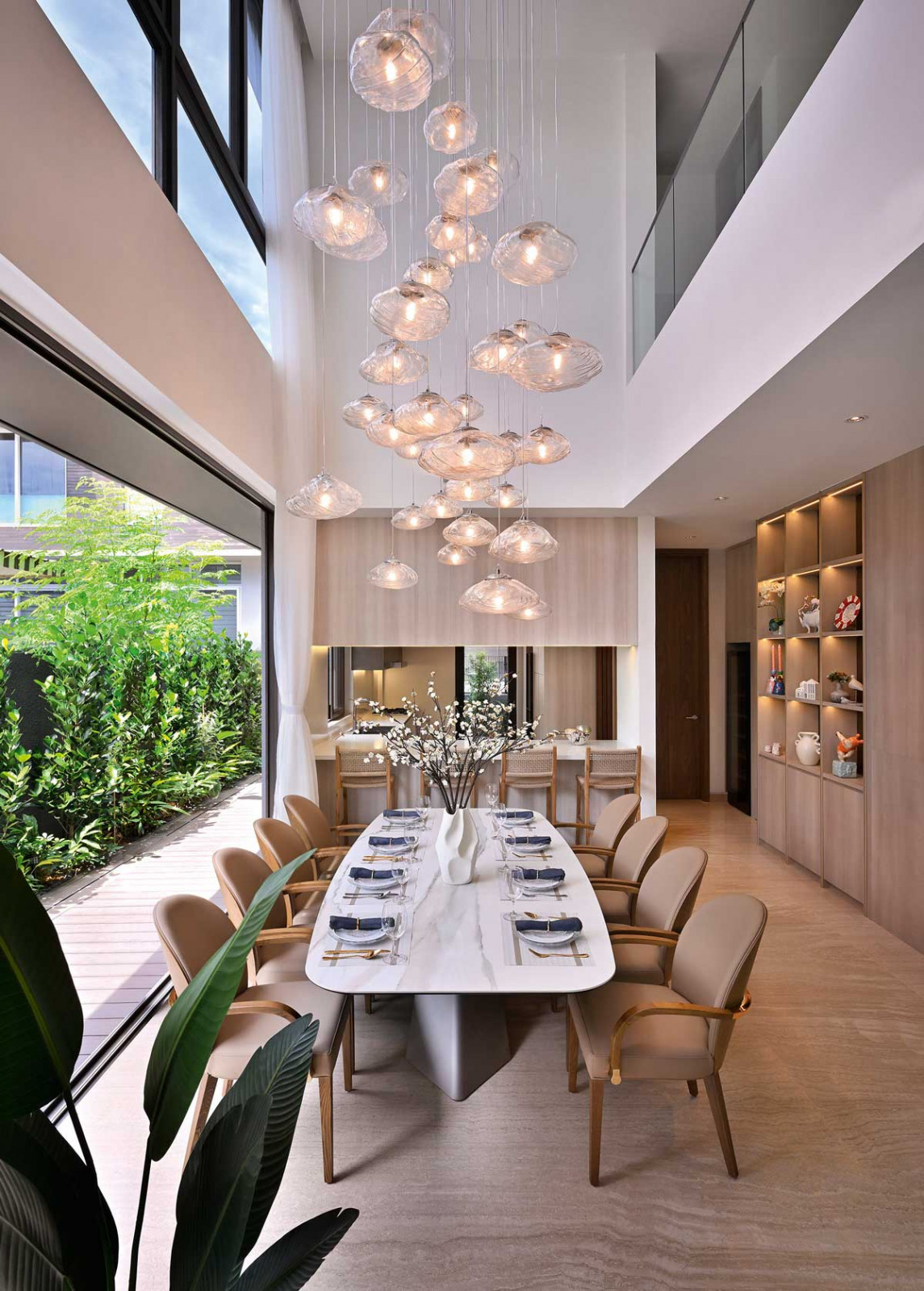 The dining area’s soaring double-volume height provides the perfect setting for a cluster of elegant pendant lights