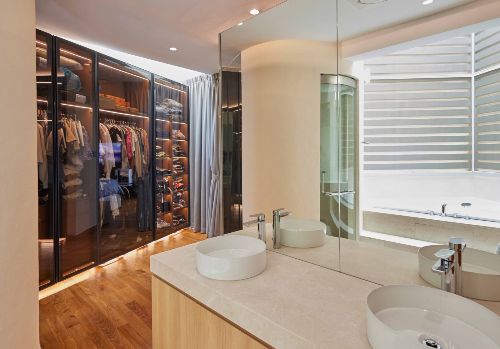 A dark glass wardrobe provides contrast against the bathroom’s lighter palette