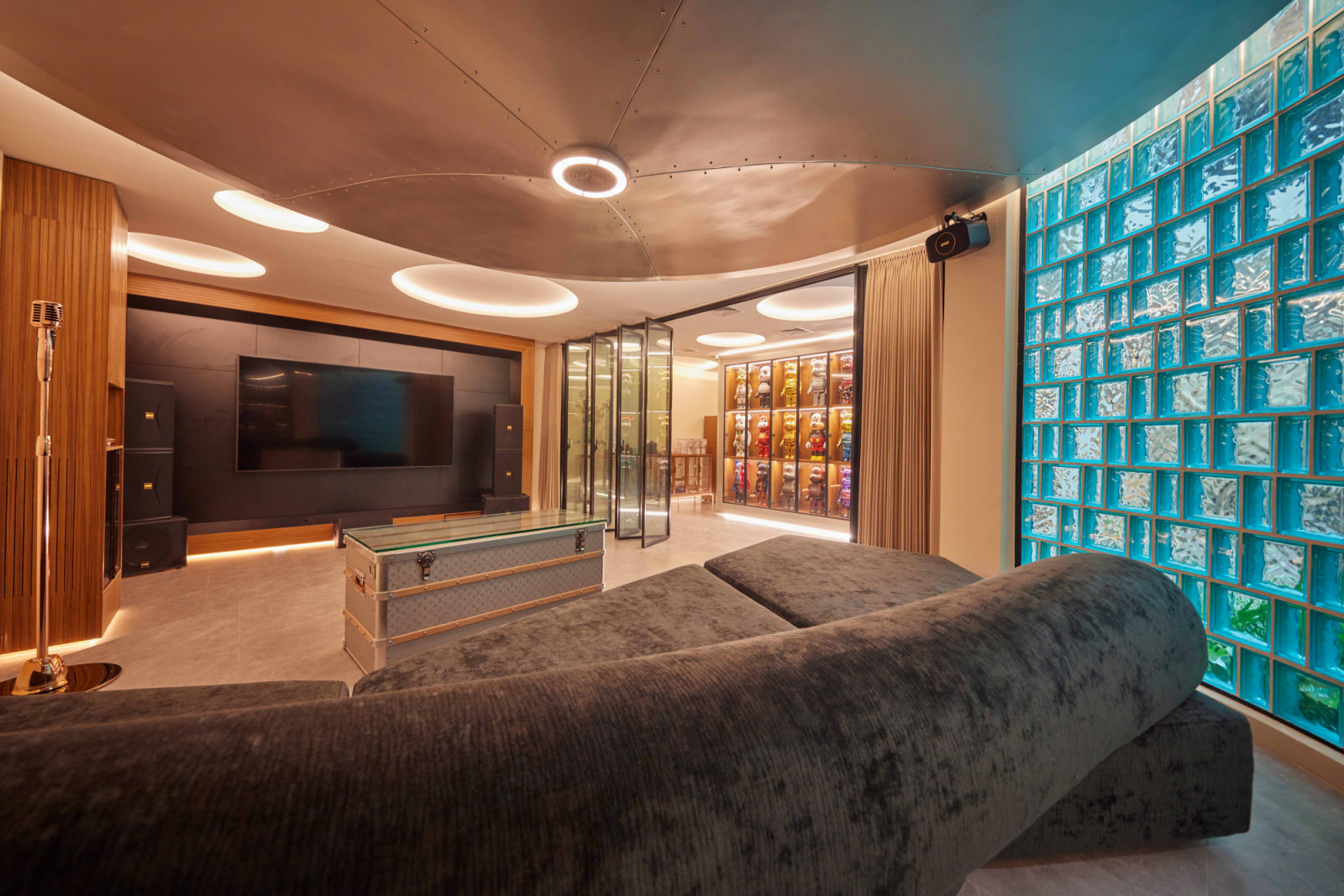 Another view of the entertainment room and its striking blue glass-block wall that offers a glimpse of the Bearbrick collection outside
