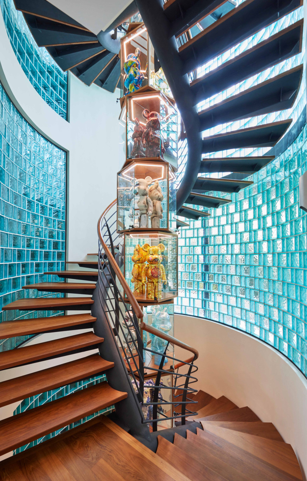 Encircling the staircase, blue glass block walls amplify the home’s pop art-inspired mood