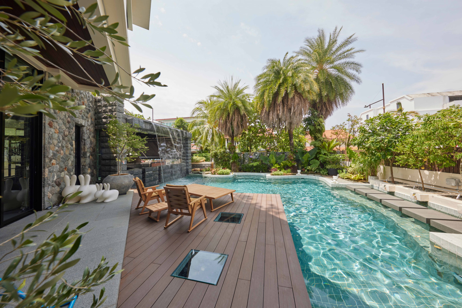 The bungalow’s lush poolscape, with a family of Qeeboo Rabbit chairs hinting at the playful nature of the interior