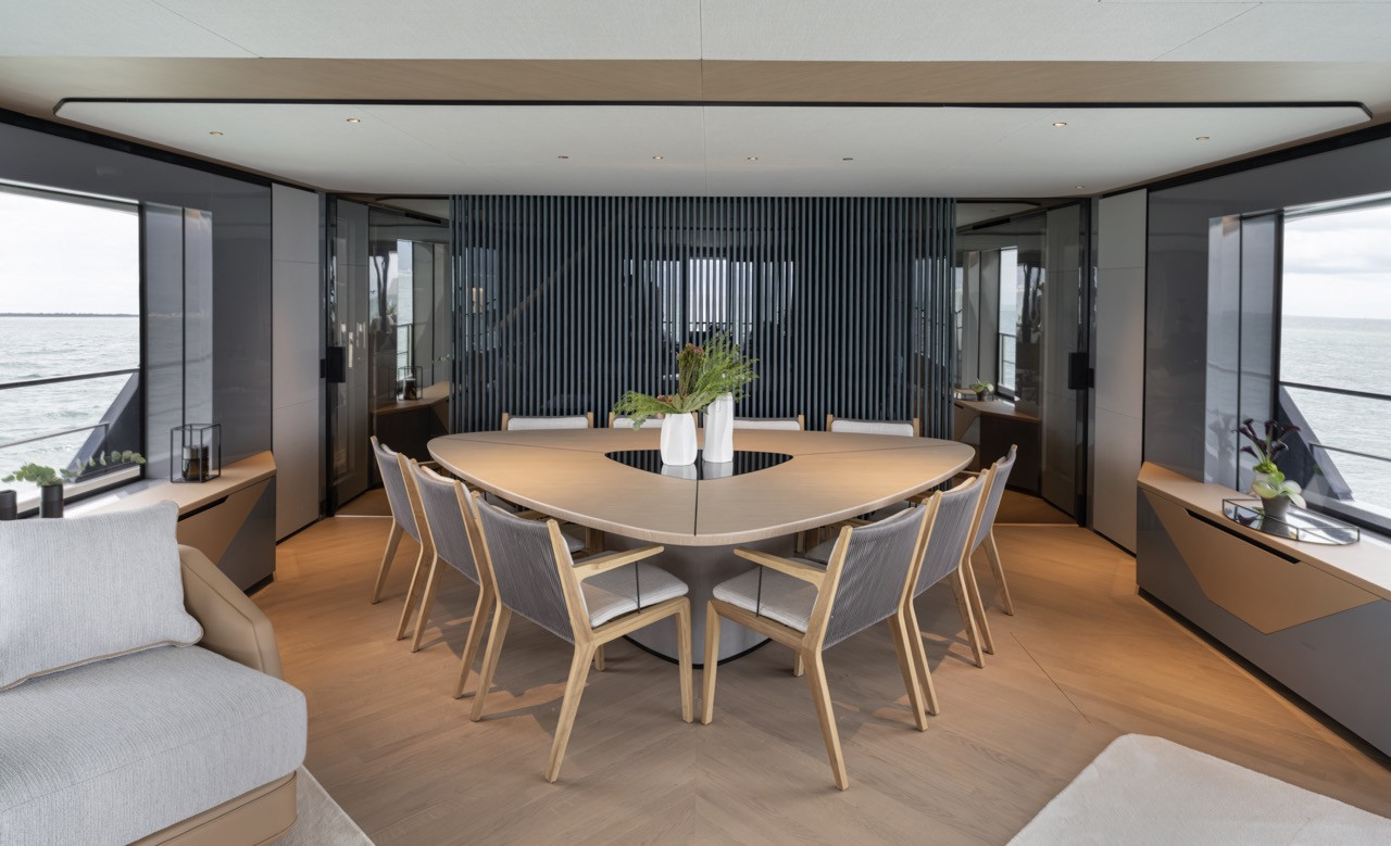 A custom dining table anchors the Azimut Grande 30M salon beneath a sculptural fluted wall that conceals technology