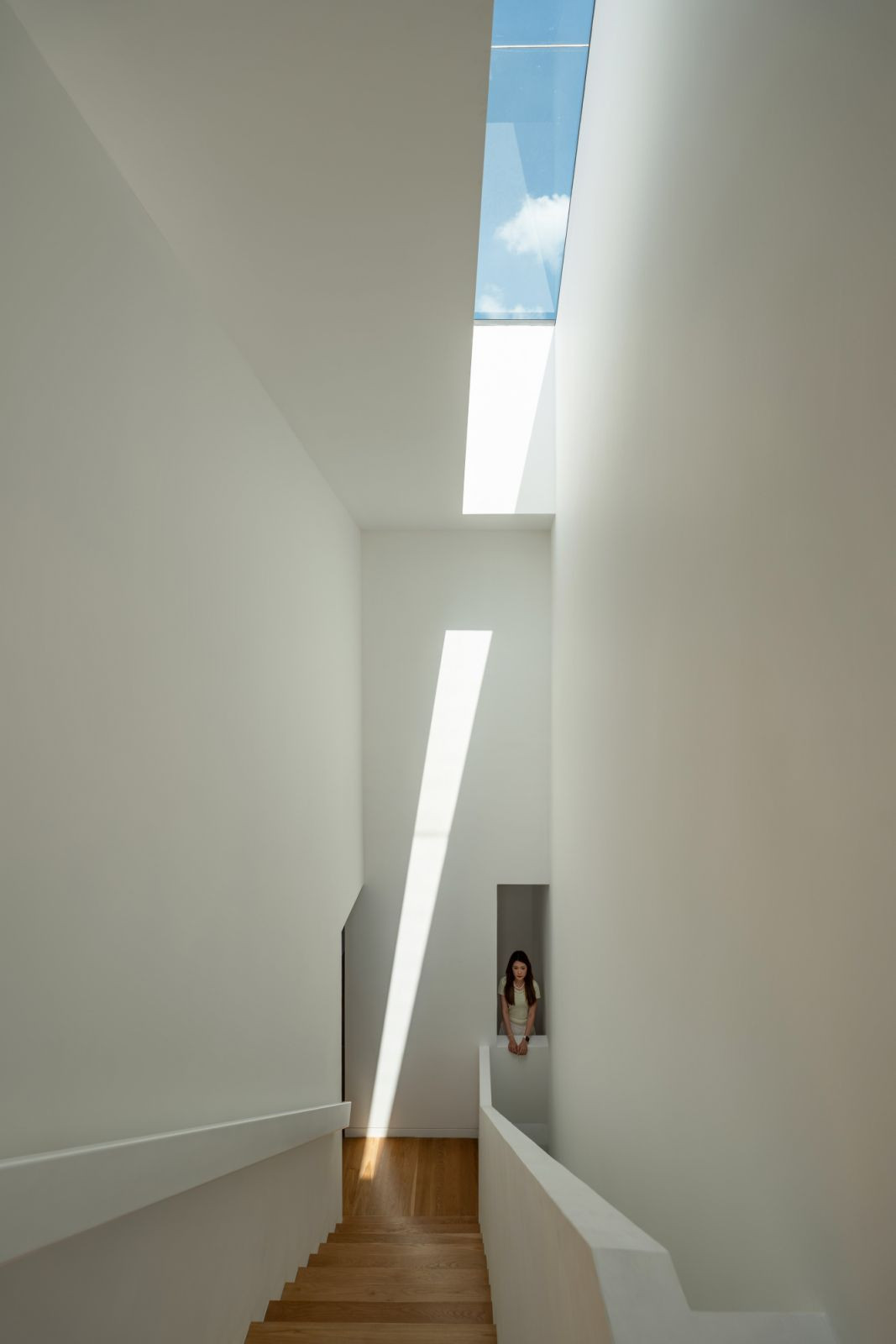 The perpendicular stairwell toward the second floor allows daylight to filter through the void (Photo: Bricksbegin)