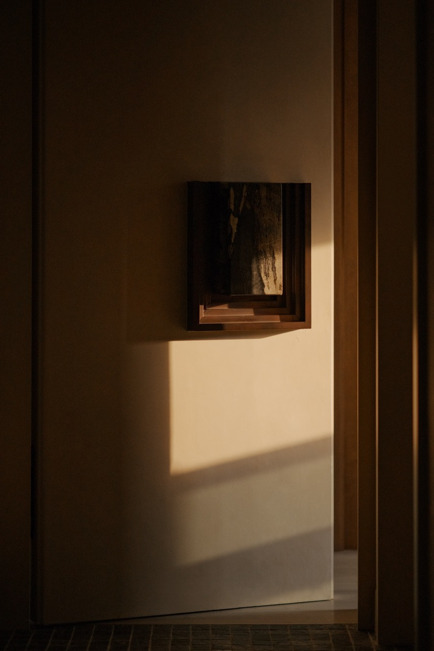 A recessed wall niche displays calligraphy art, backlit to create depth in the corridor