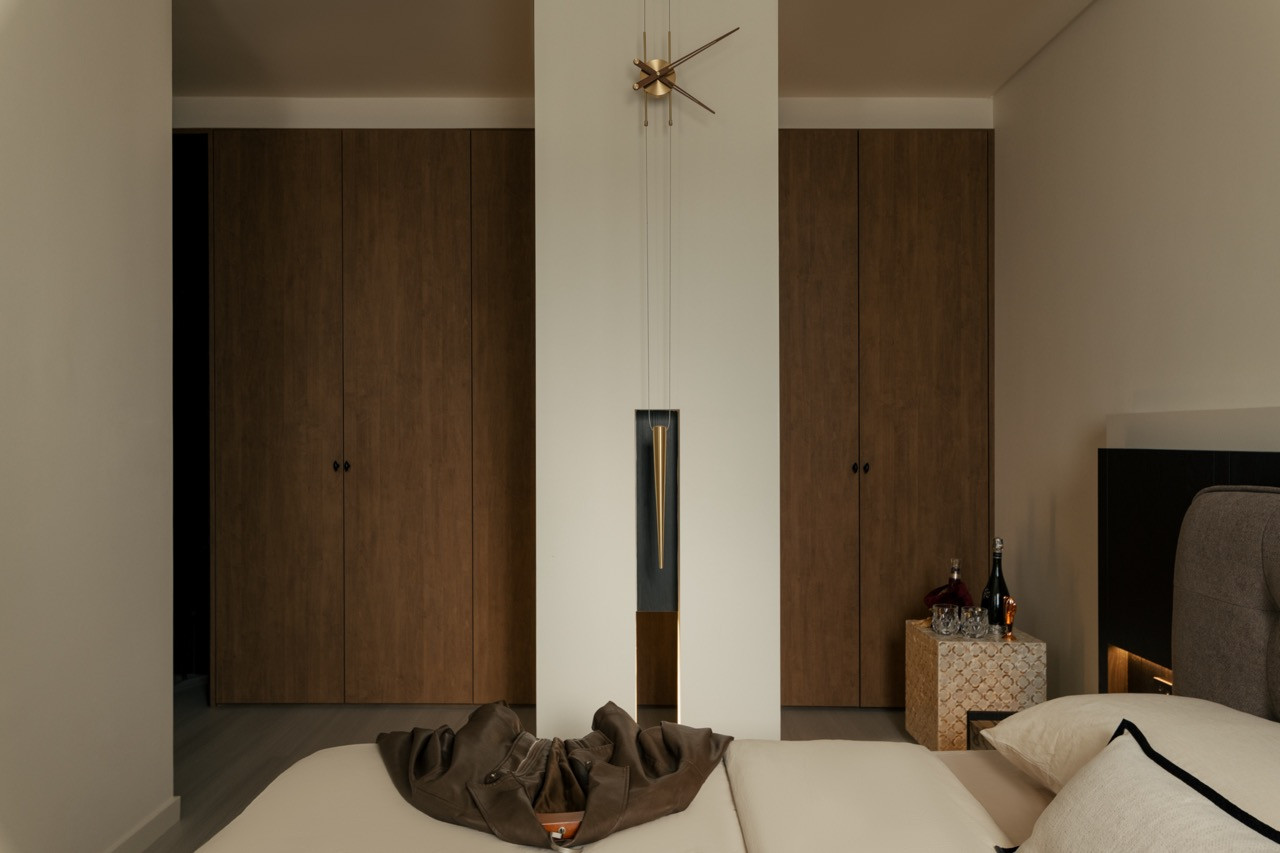 Floor-to-ceiling walnut-stained wardrobes frame the upholstered bed in the master bedroom's minimal design scheme