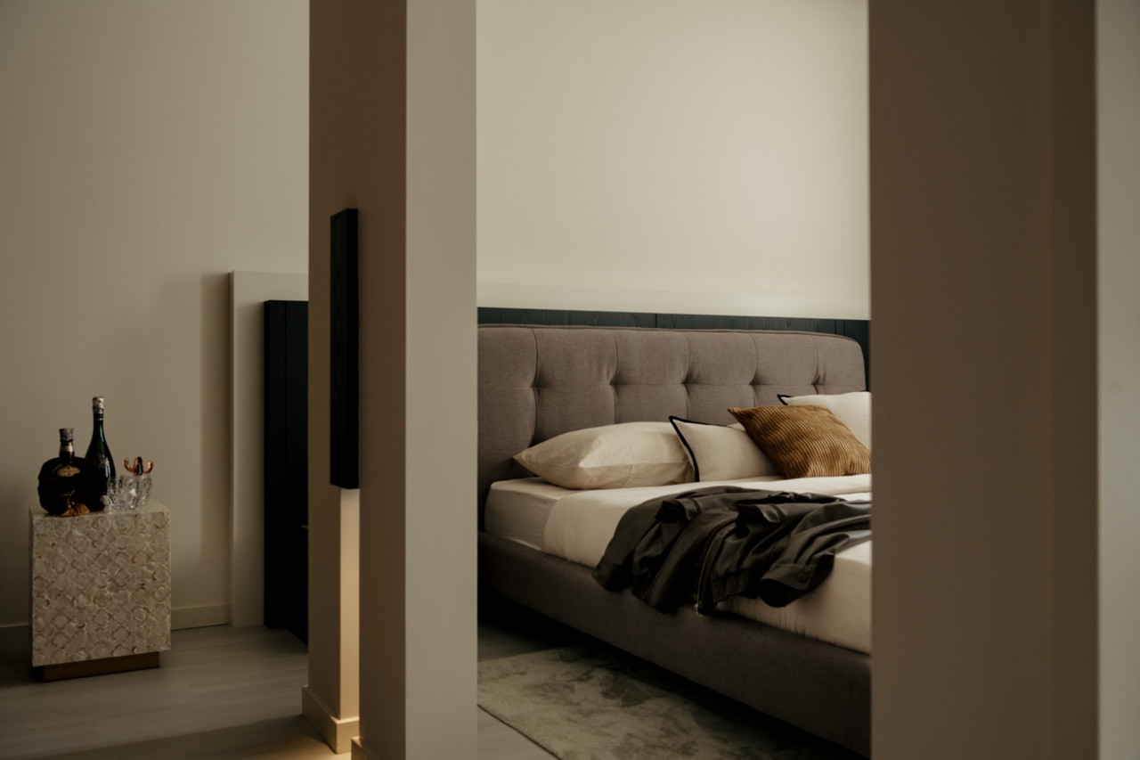 A view from the corridor into the master bedroom reveals the integration of the stone pedestal and earth-toned limewash walls