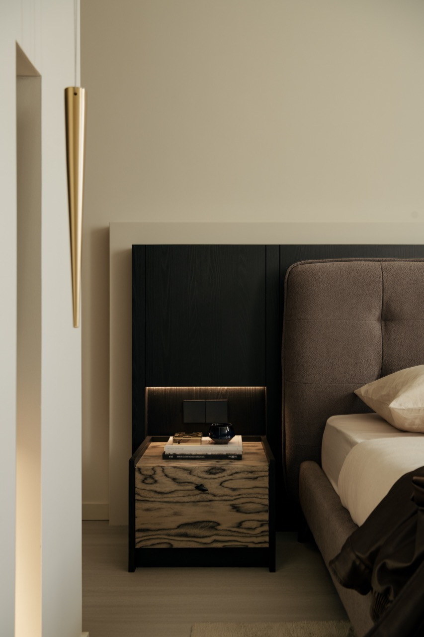 The master bedroom features black cabinetry with integrated lighting and a bedside table finished in wood-grain laminate