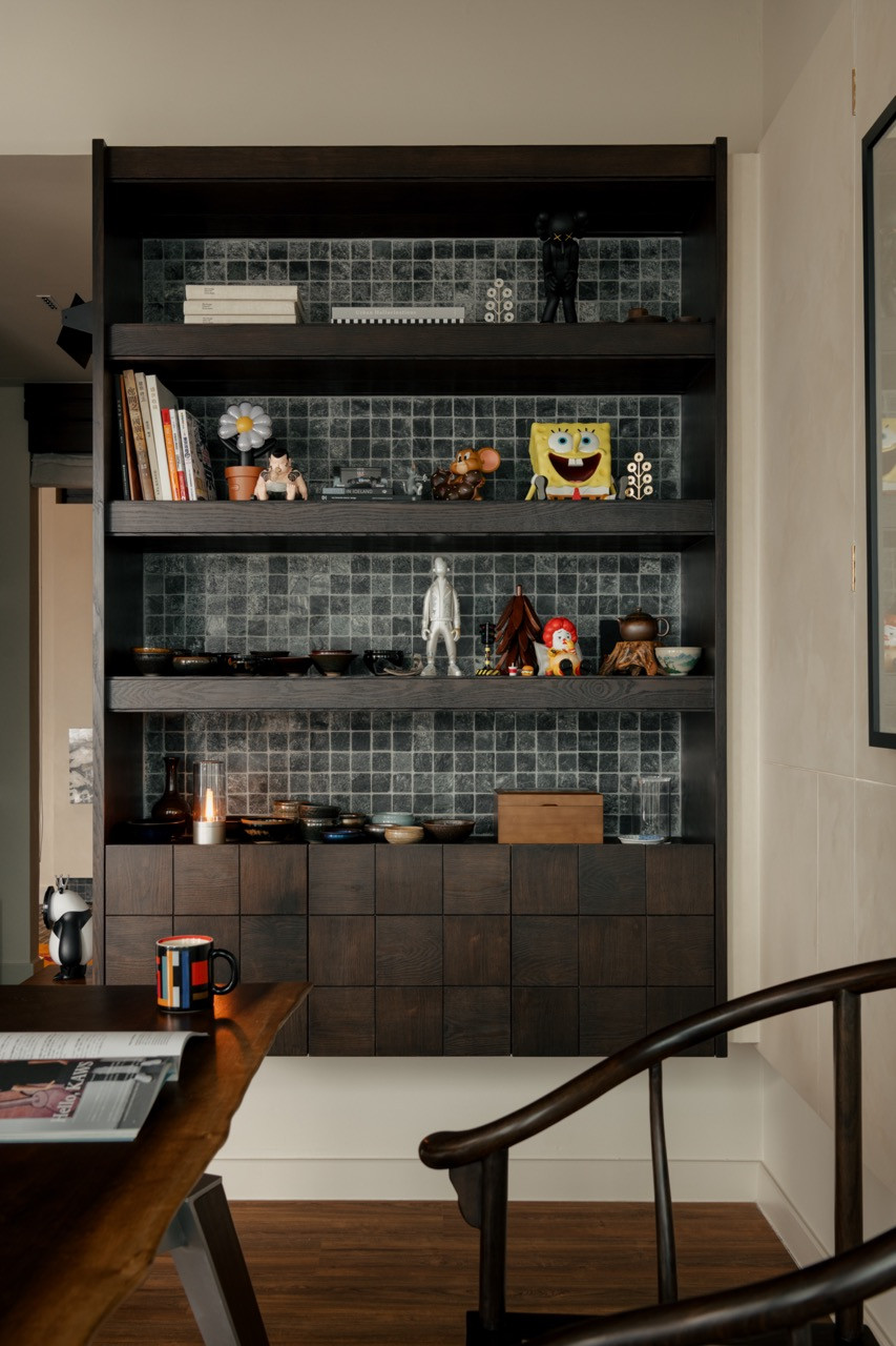 The home office features built-in walnut-stained shelving with silver quartz mosaic tile backing to display Bob’s curated collection