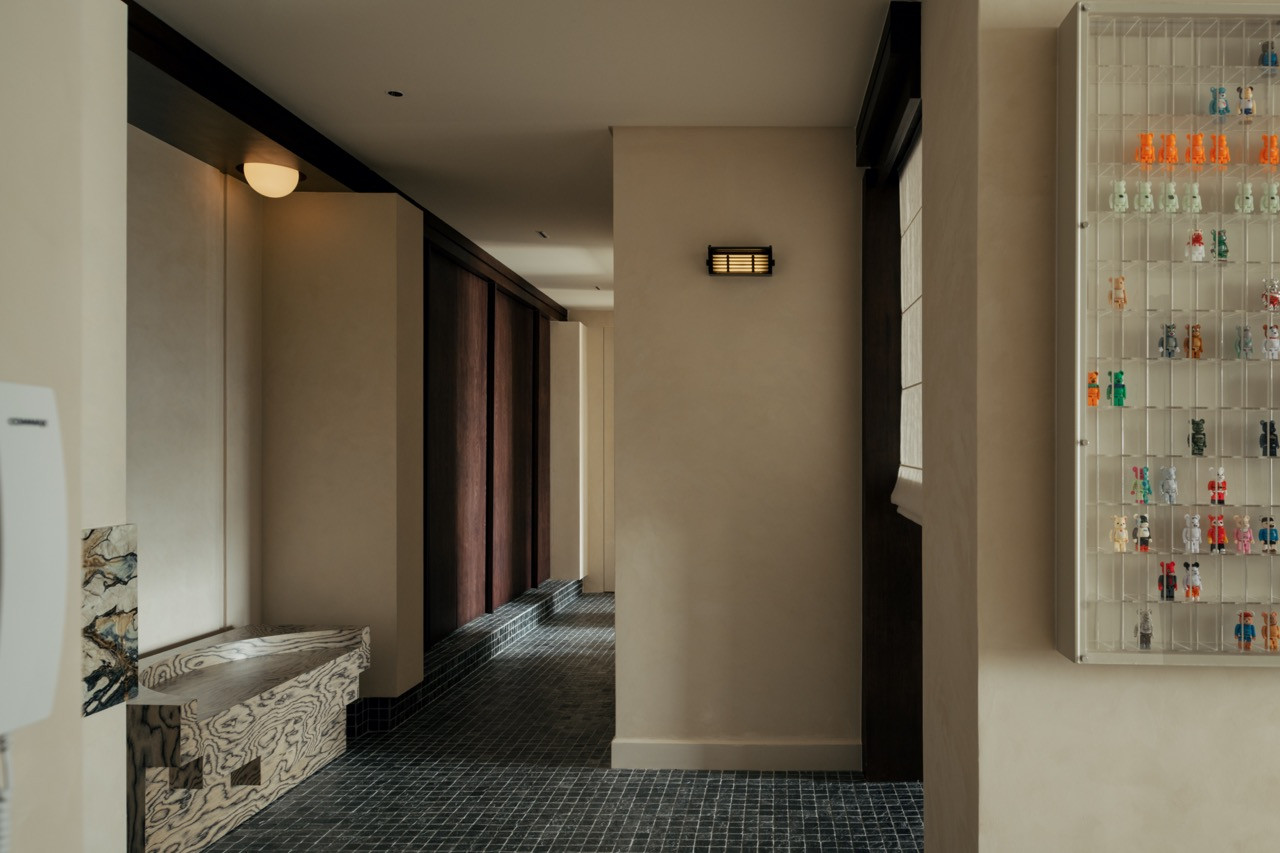 The entrance area features silver quartz mosaic flooring, solid wood louvre doors leading to the home office, and display shelving for Bob's collection