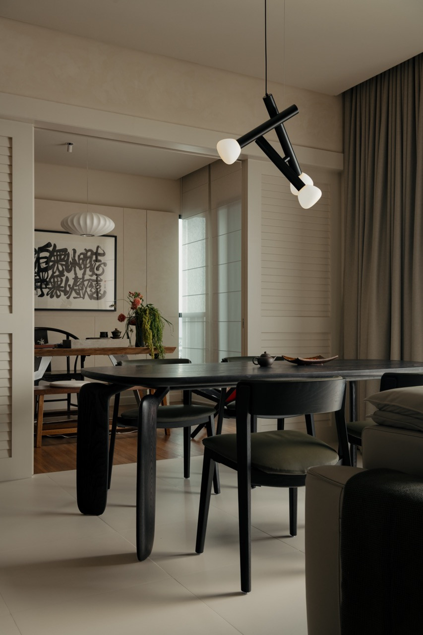 The open-plan dining and living area connects through to the home office, where the calligraphy art is visible beyond